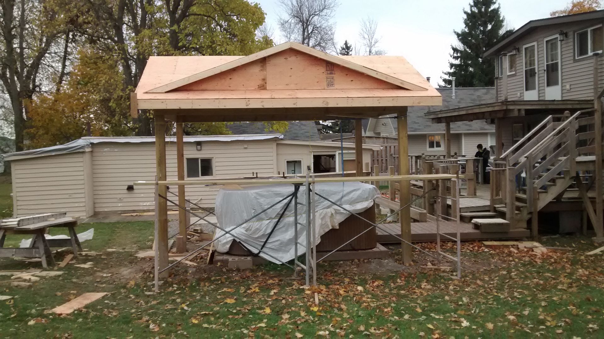 A wooden structure is being built in the backyard of a house.