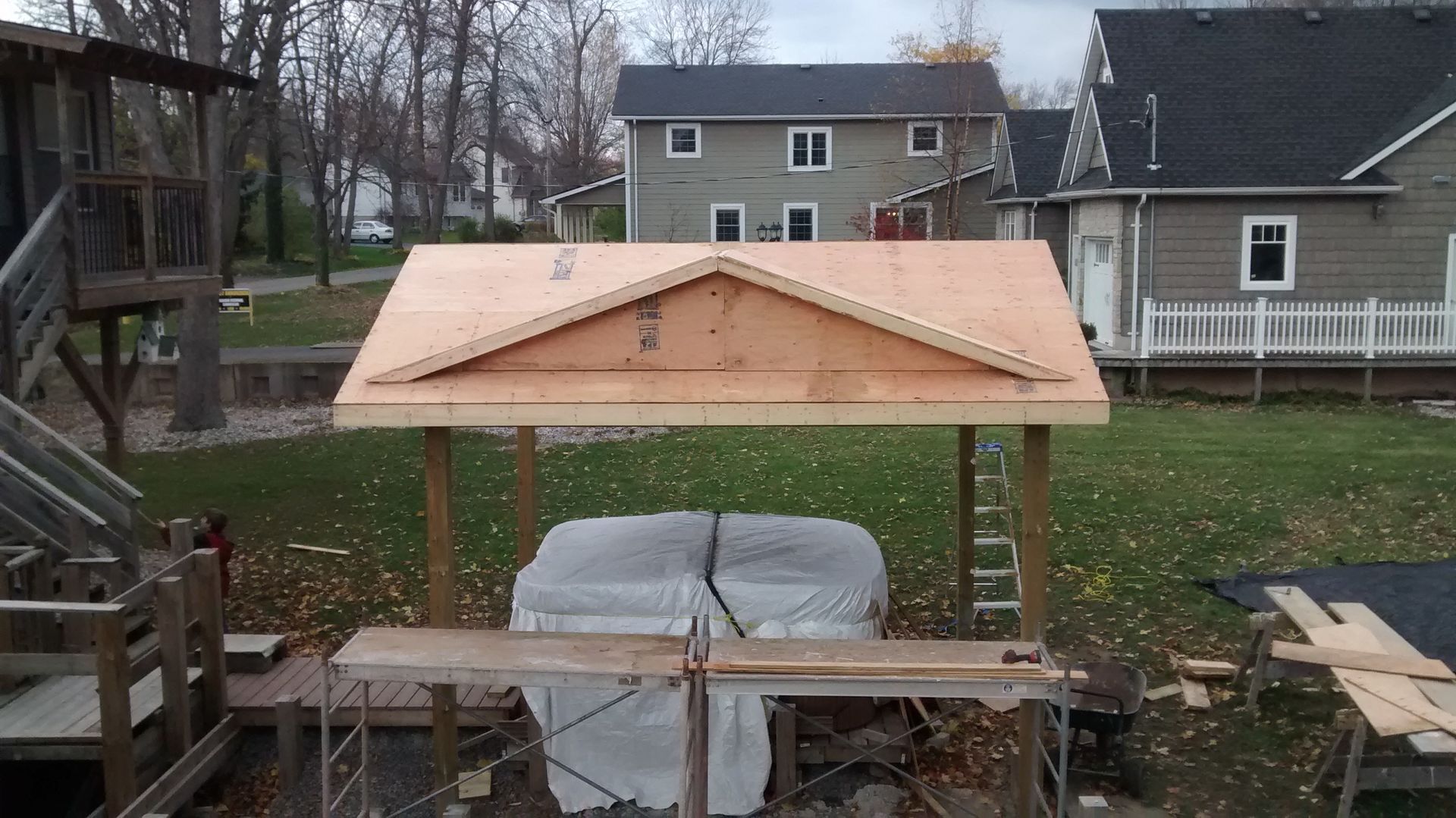 A wooden structure is being built over a hot tub in a backyard.