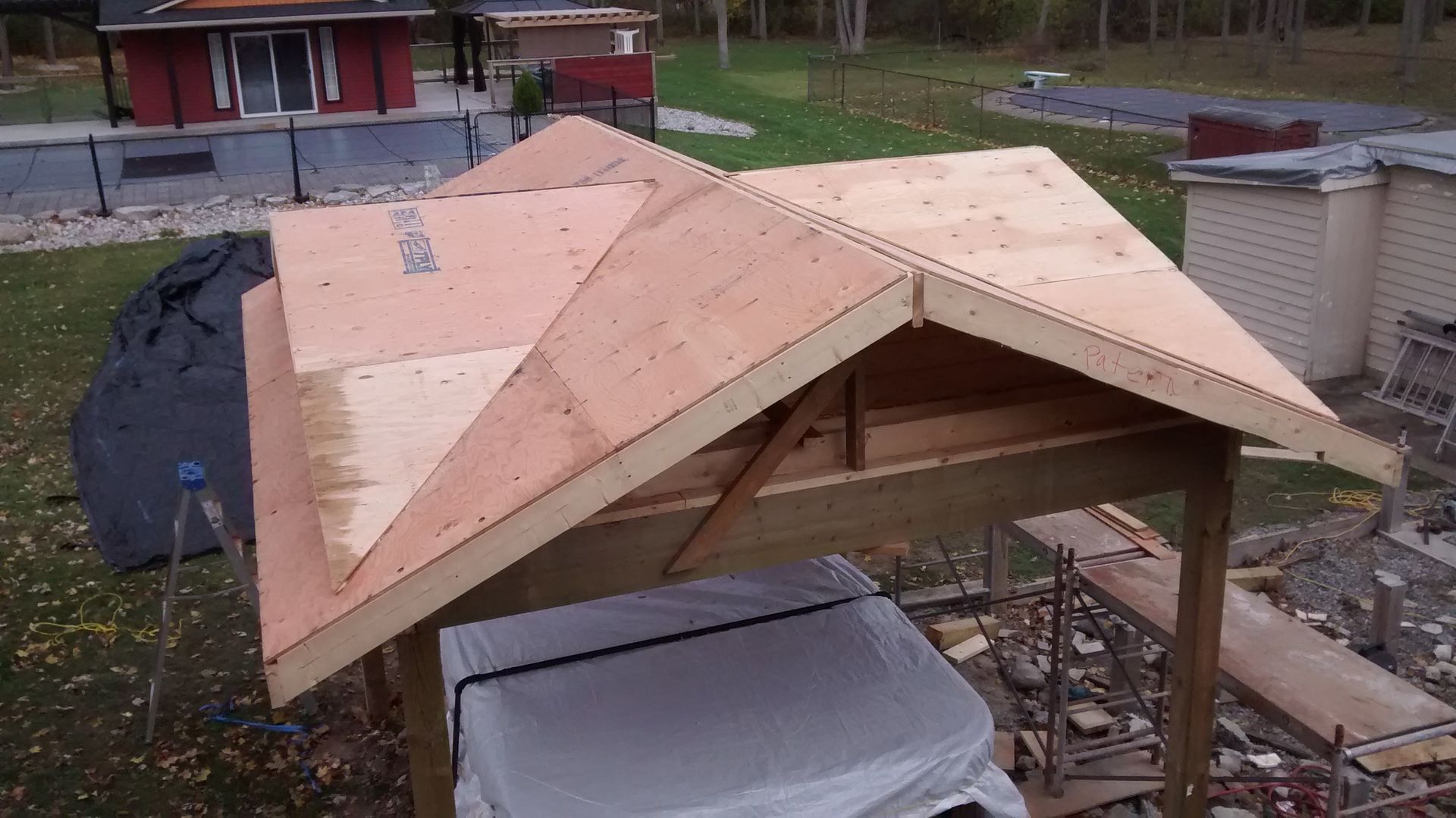 A wooden roof is being built in a backyard