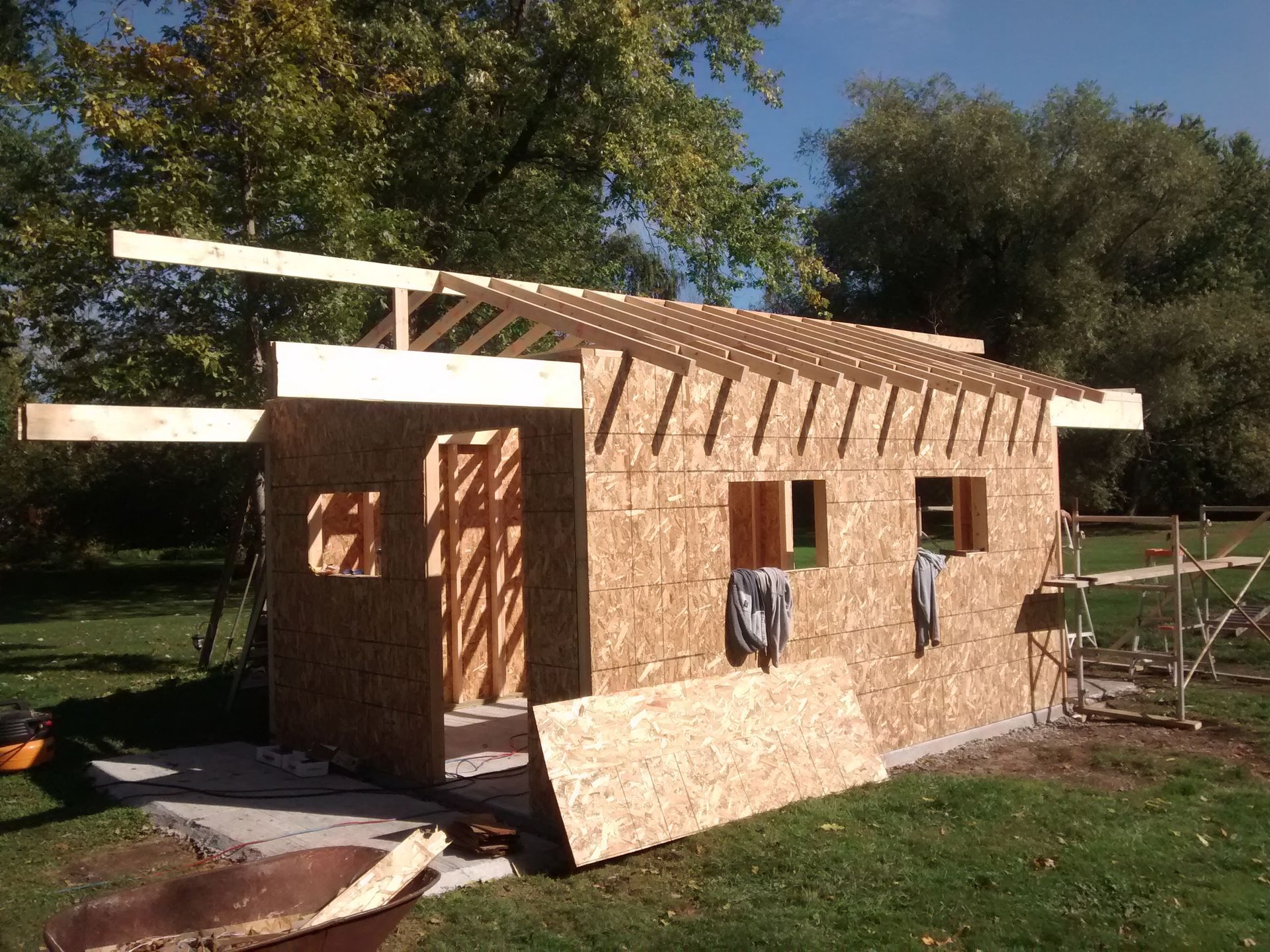 A wooden shed is being built in a backyard