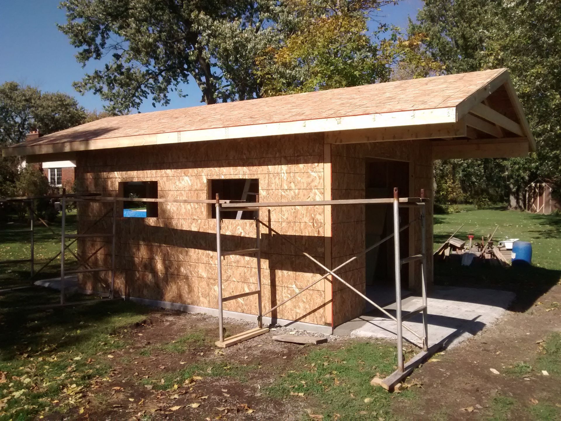 A shed is being built in a backyard with scaffolding around it