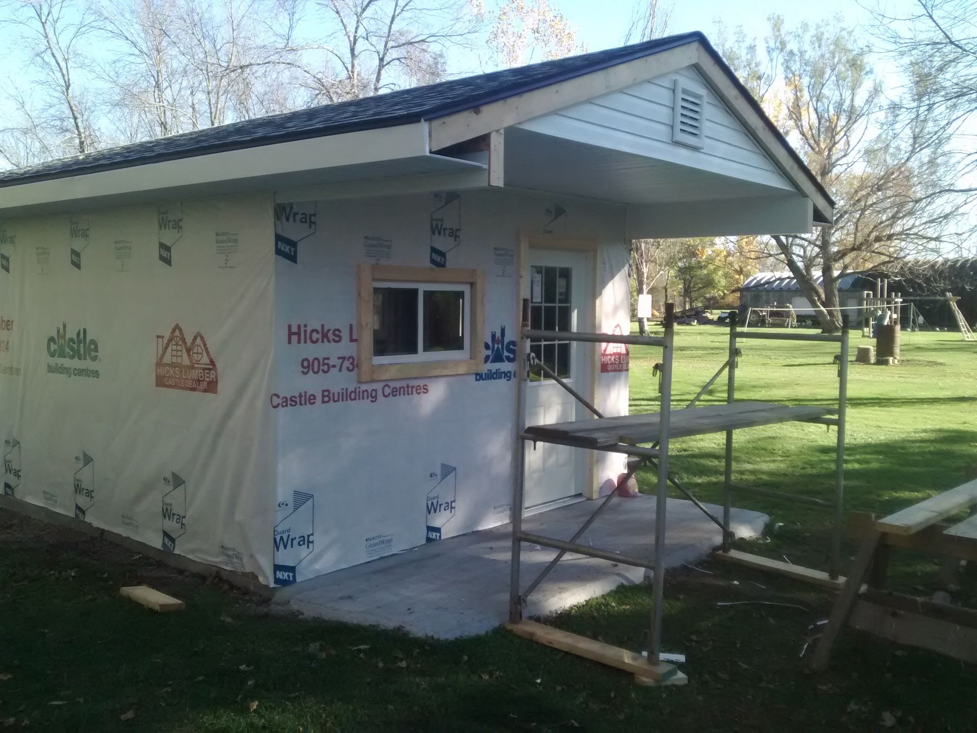 A shed is being built with a window and scaffolding