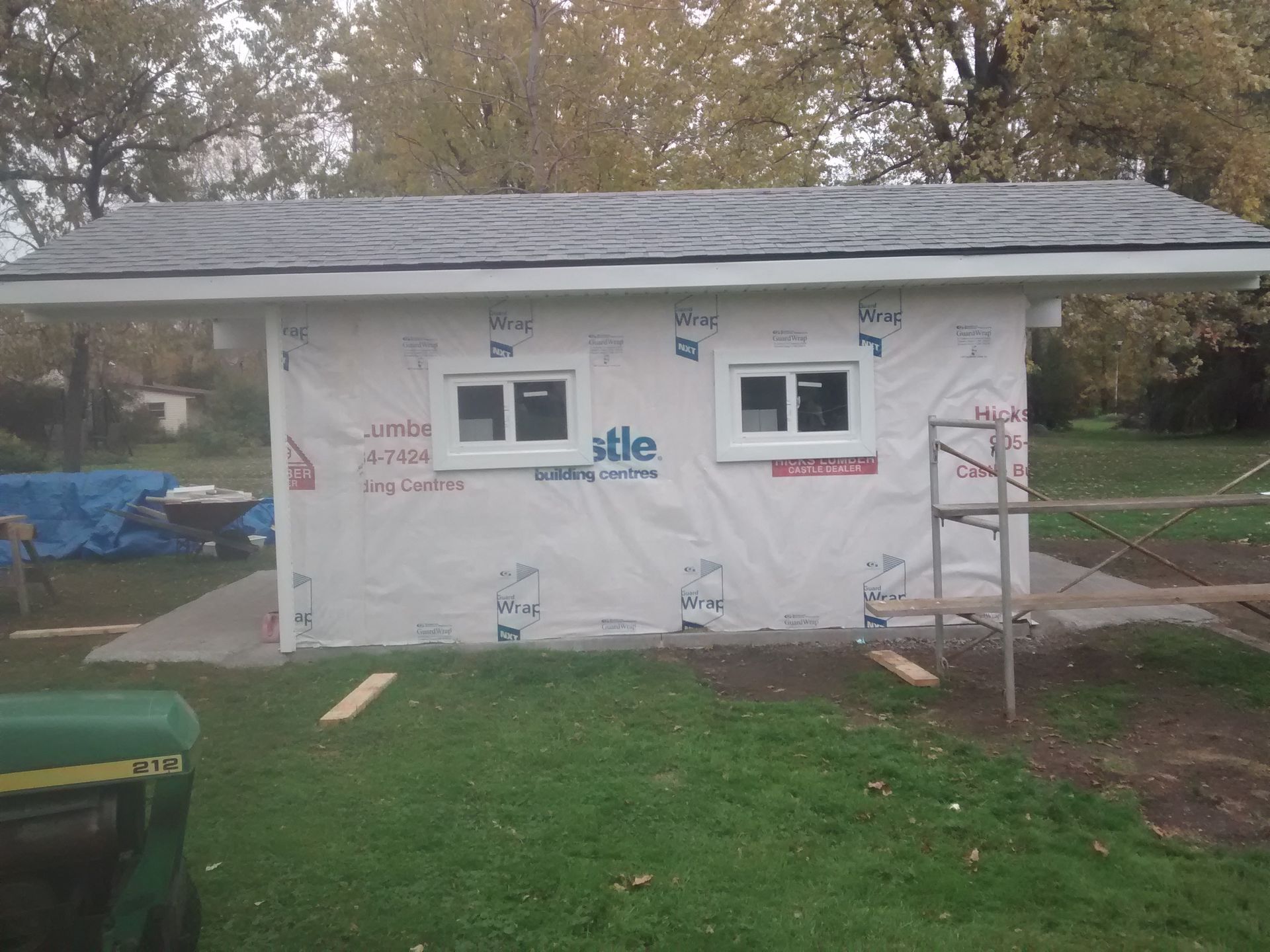 A green john deere tractor is parked in front of a building under construction