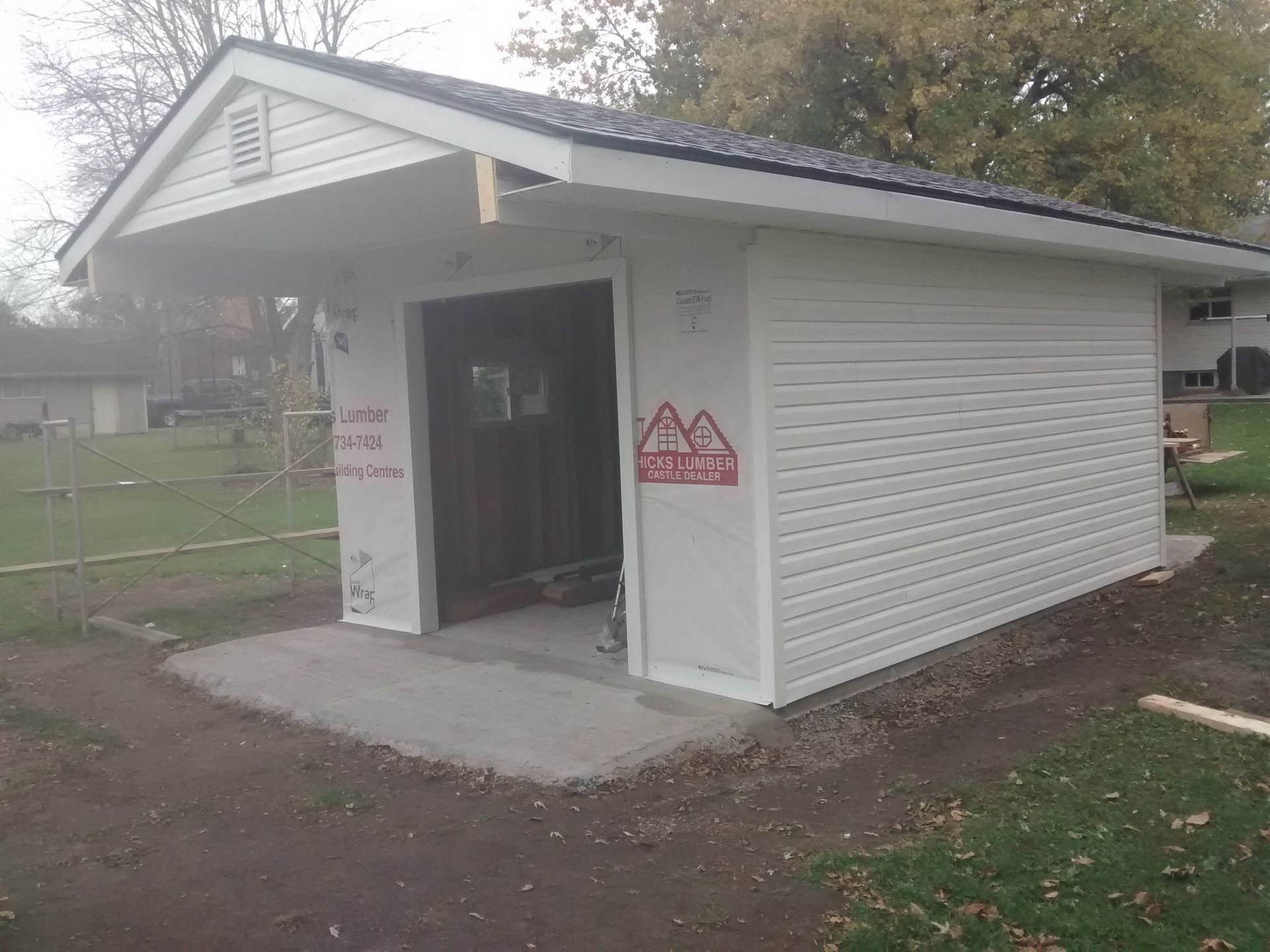 A white garage with a roof is being built in a backyard.