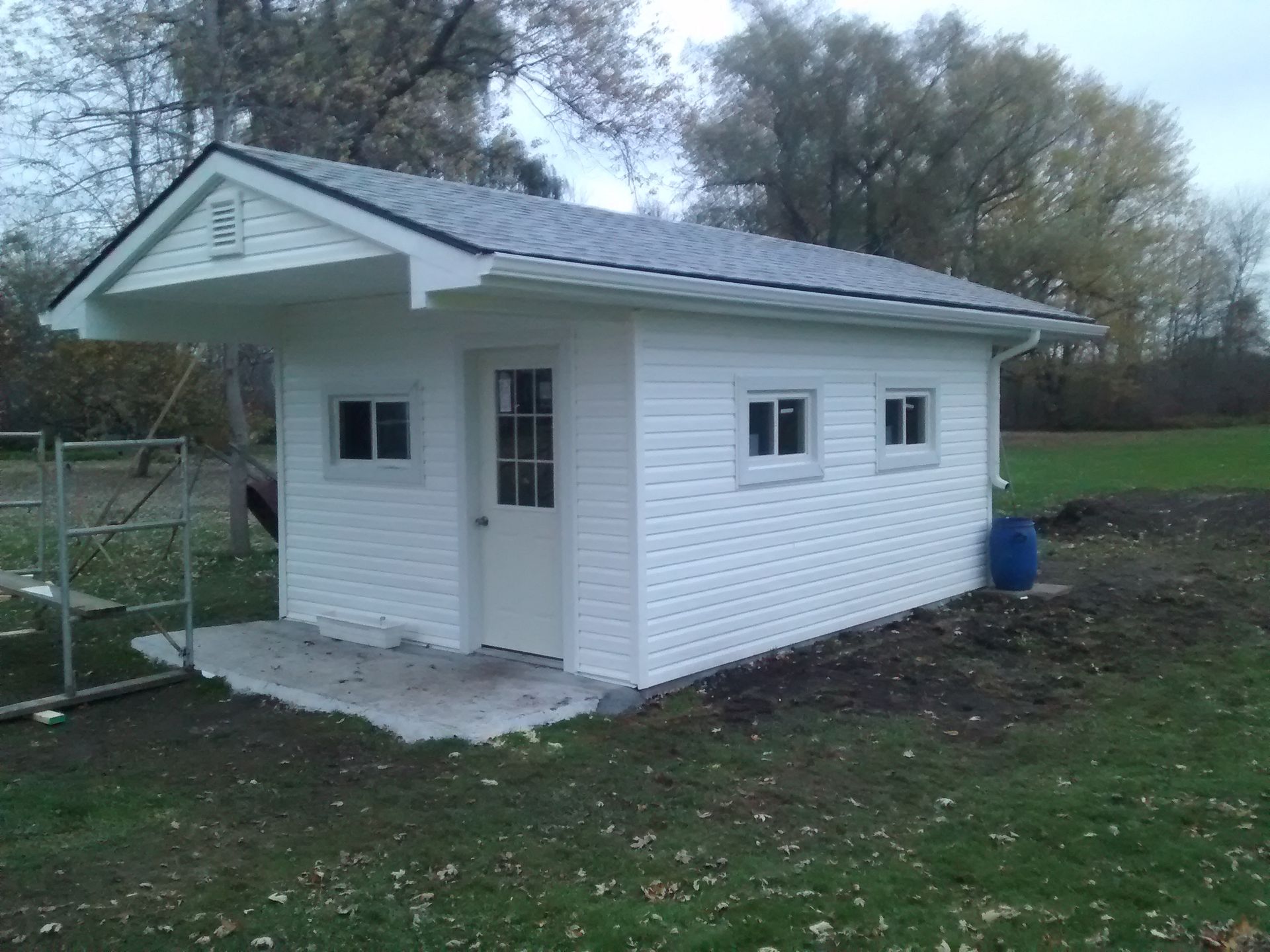 A small white shed with a gray roof