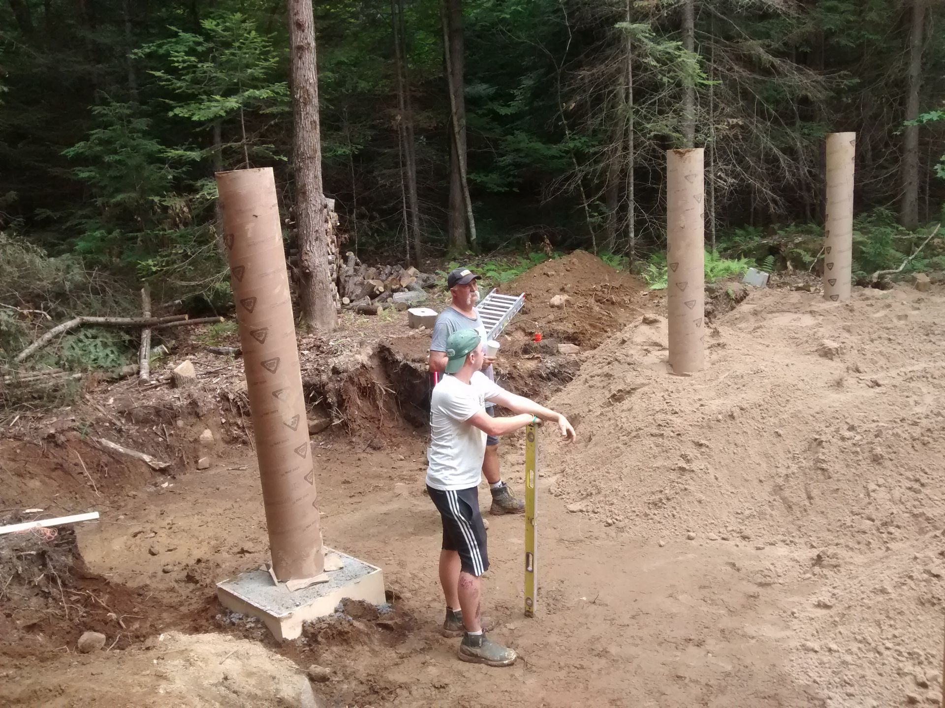 Two men are measuring a pile of dirt with a tape measure