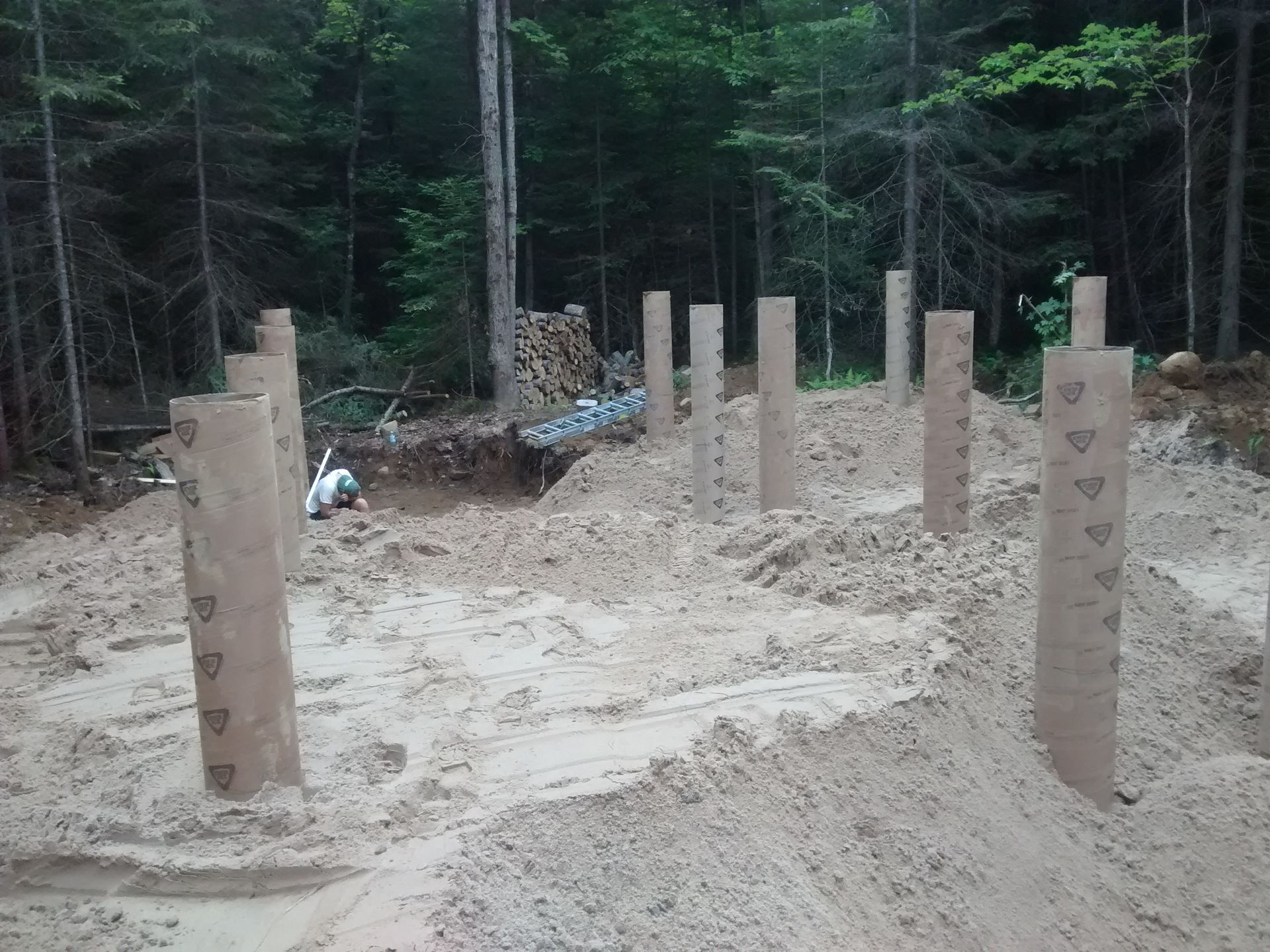 A bunch of pillars are sitting in the dirt in the middle of a forest.