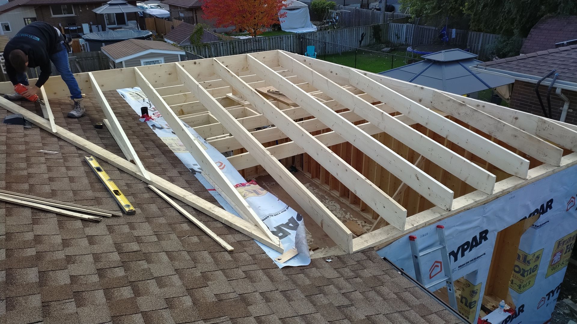 A man is working on a wooden structure on top of a roof.