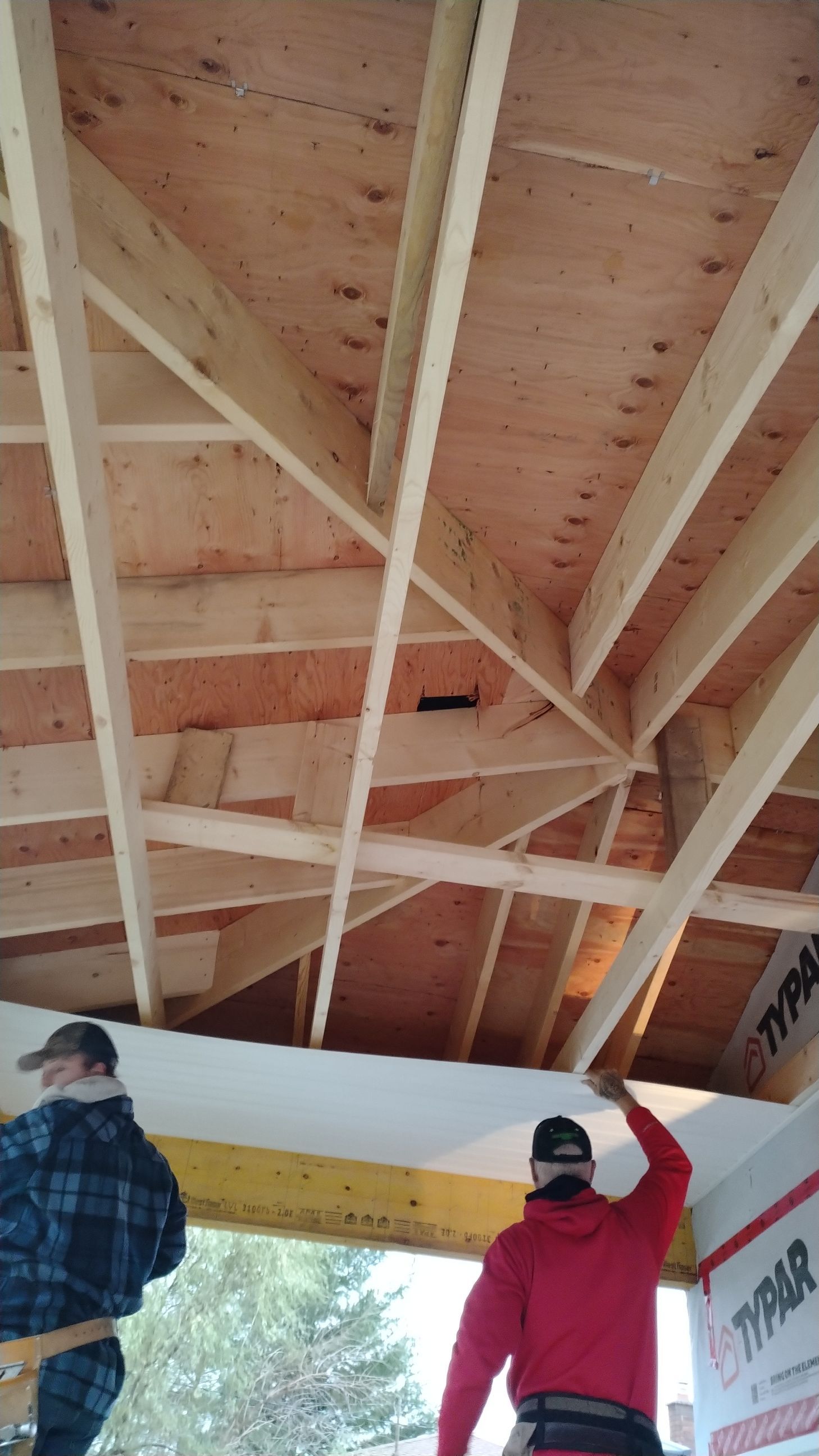 Two men are working on the ceiling of a building.