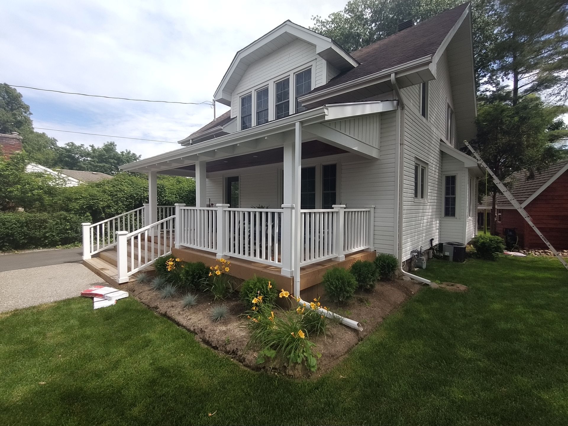 A white house with a large porch and a ramp