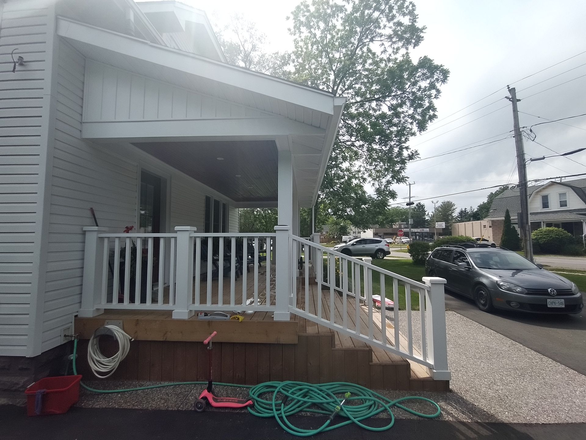 A white house with a porch and a car parked in front of it
