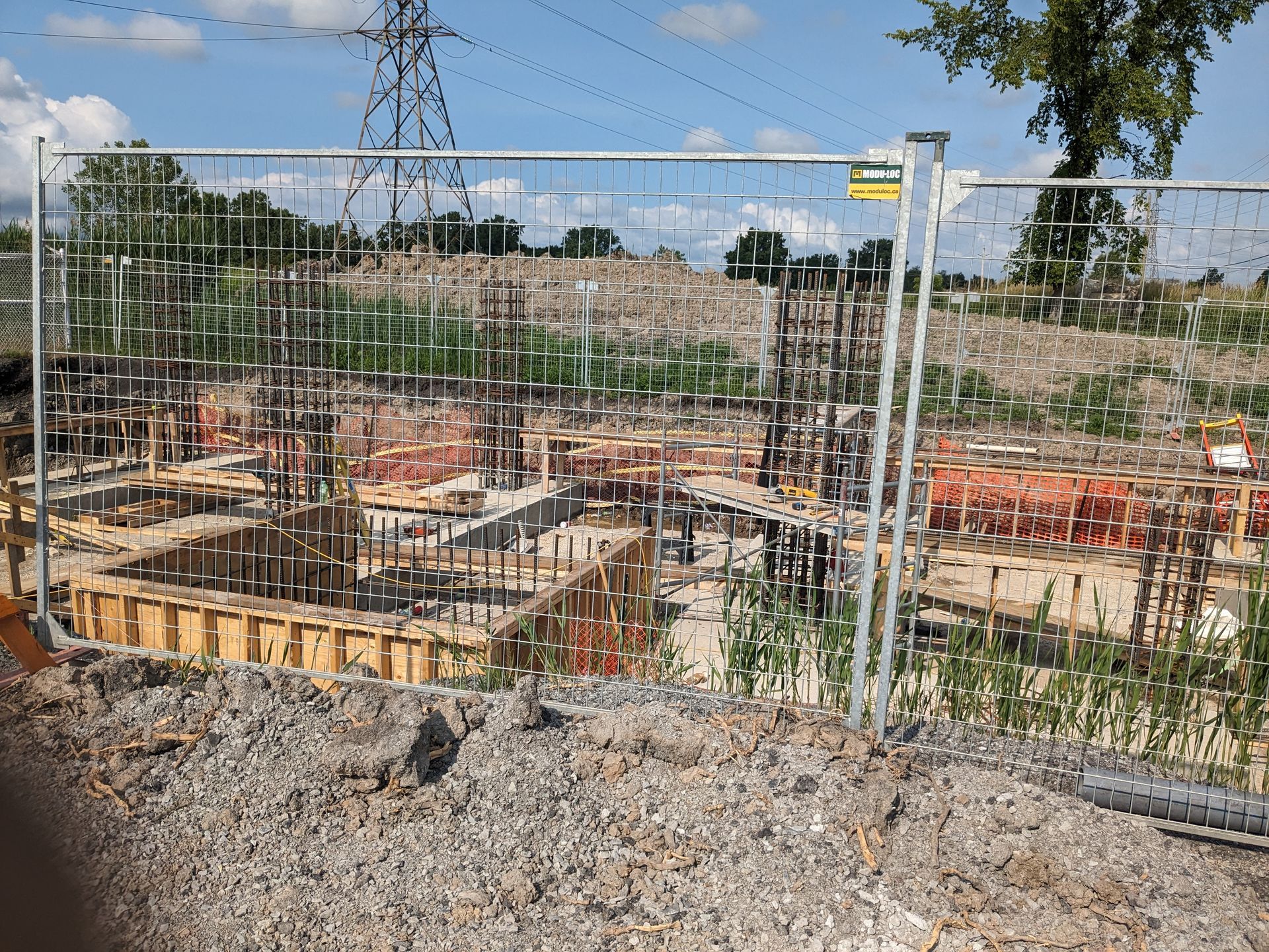 A construction site is behind a metal fence.