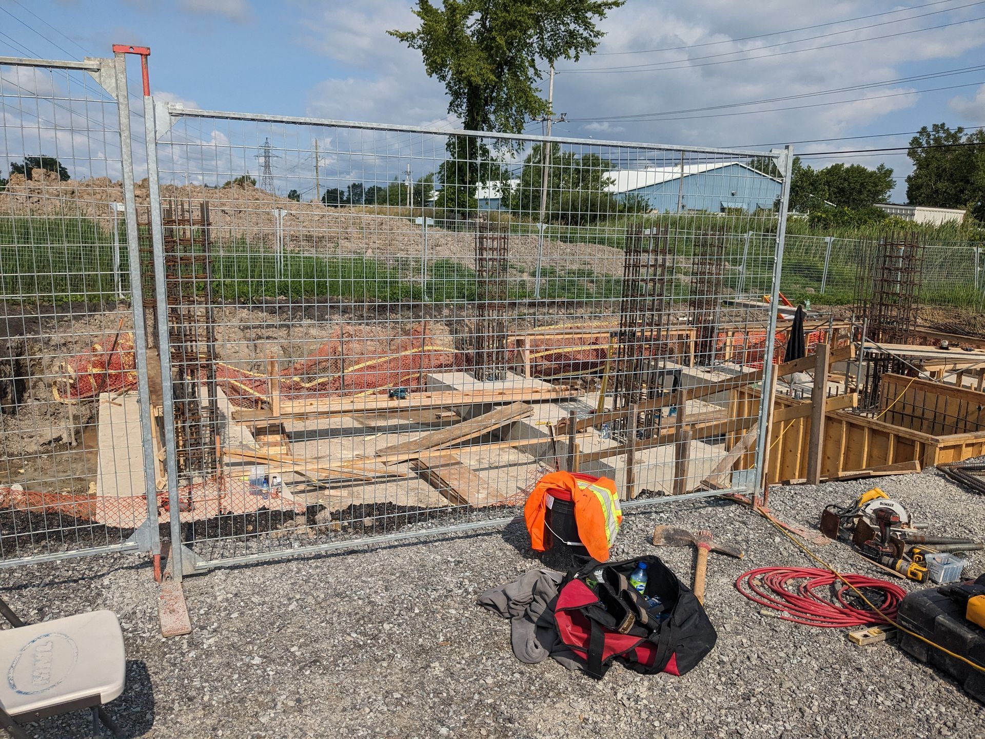 A construction site with a fence and a bag of tools on the ground.