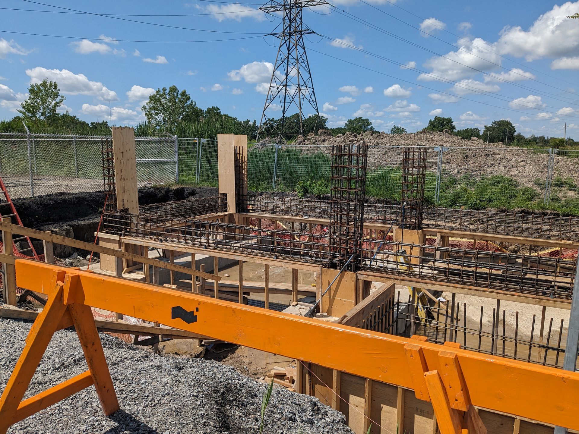 A construction site with a fence and a power line in the background.
