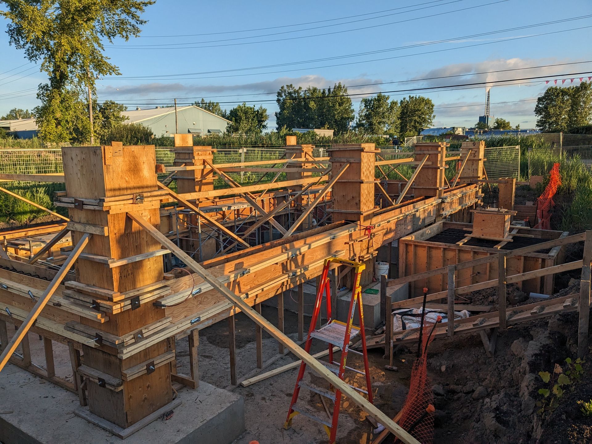 A construction site with a lot of wooden pillars and a ladder.