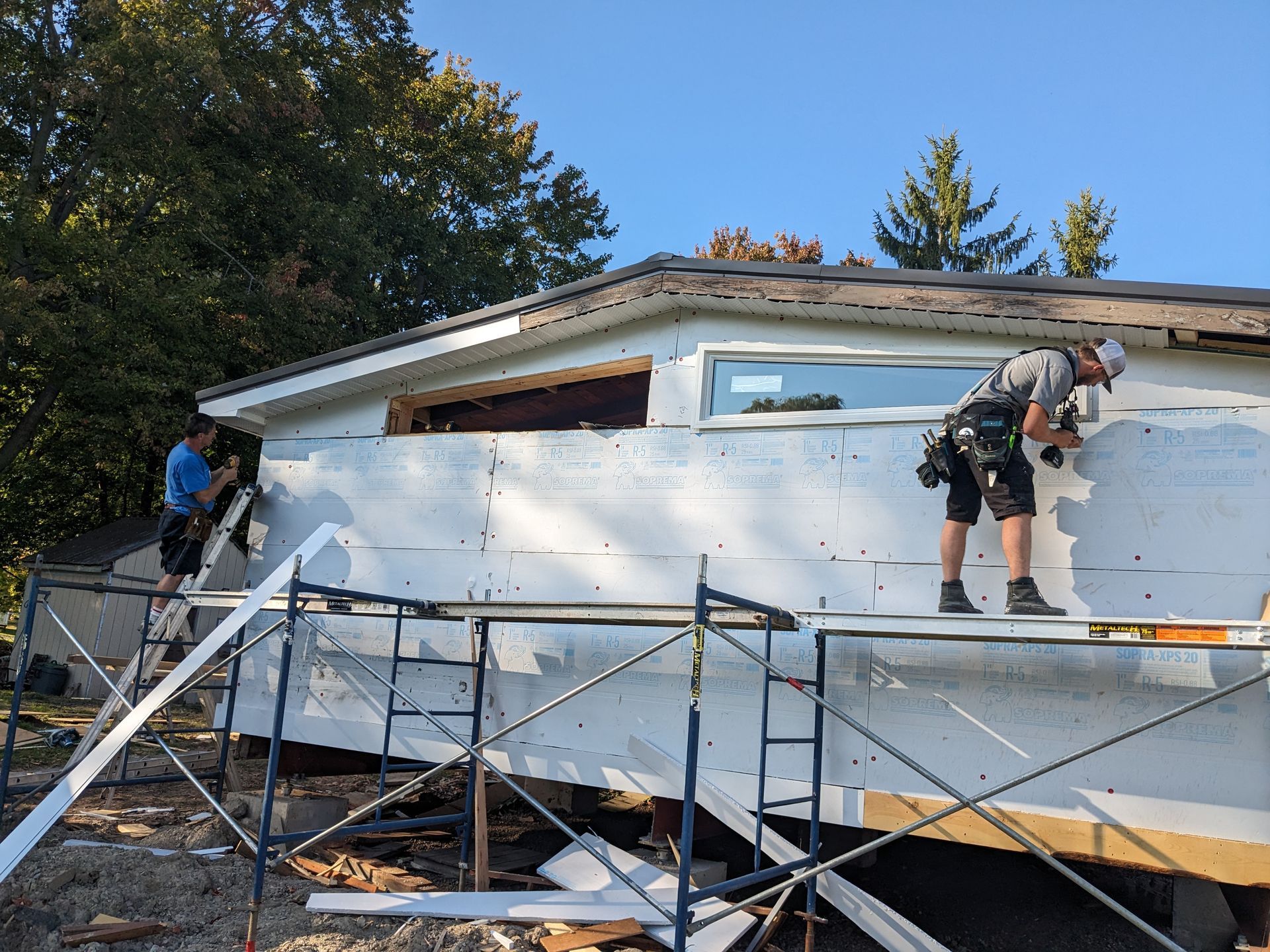 Two men are working on the side of a house.