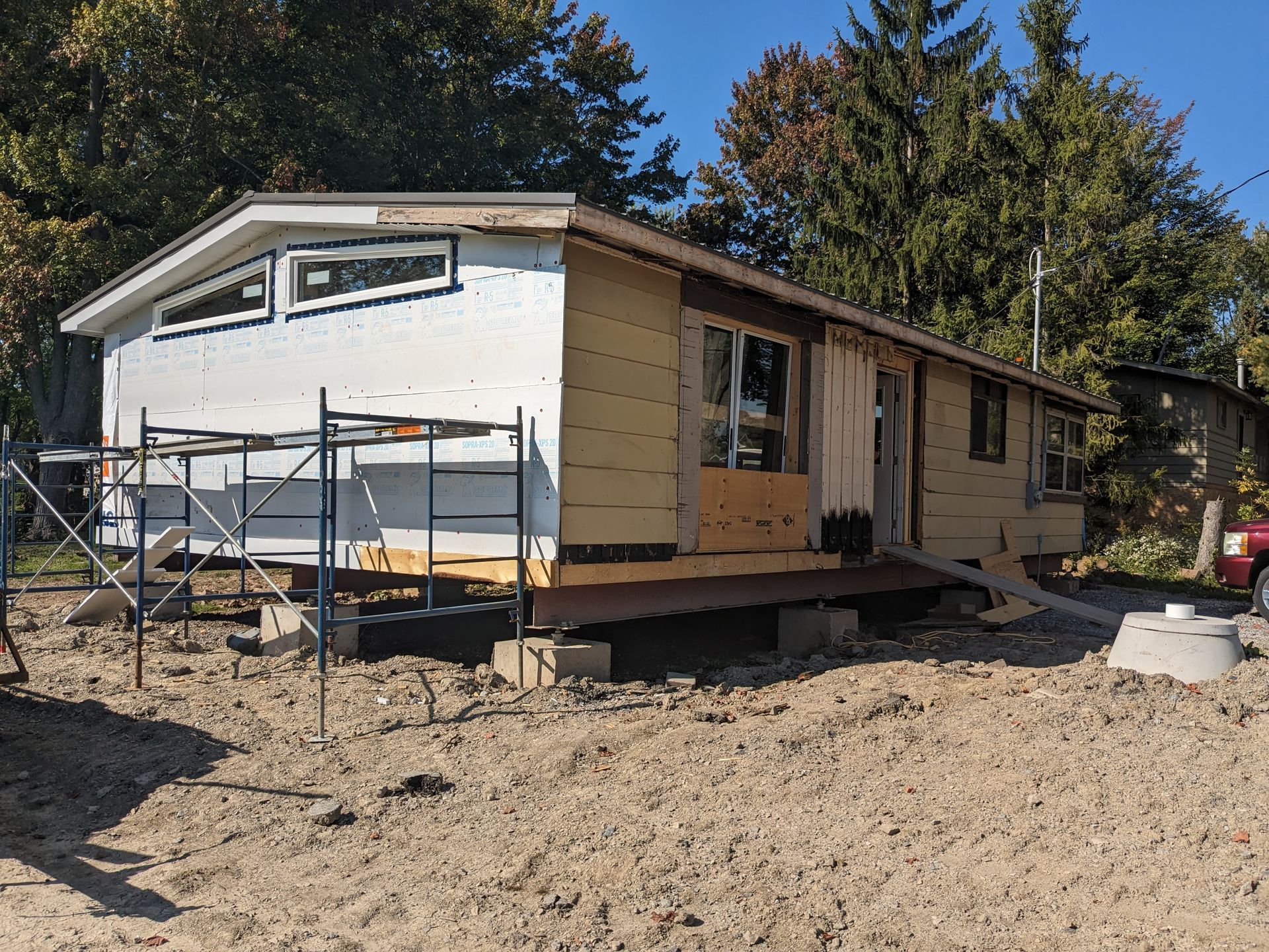 A mobile home is being built on a dirt field.