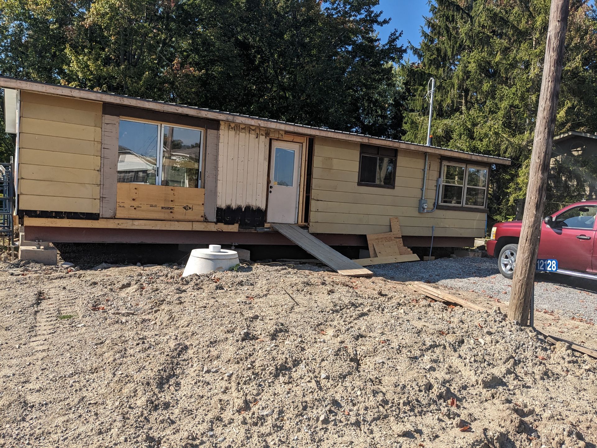 A red truck is parked in front of a mobile home under construction.