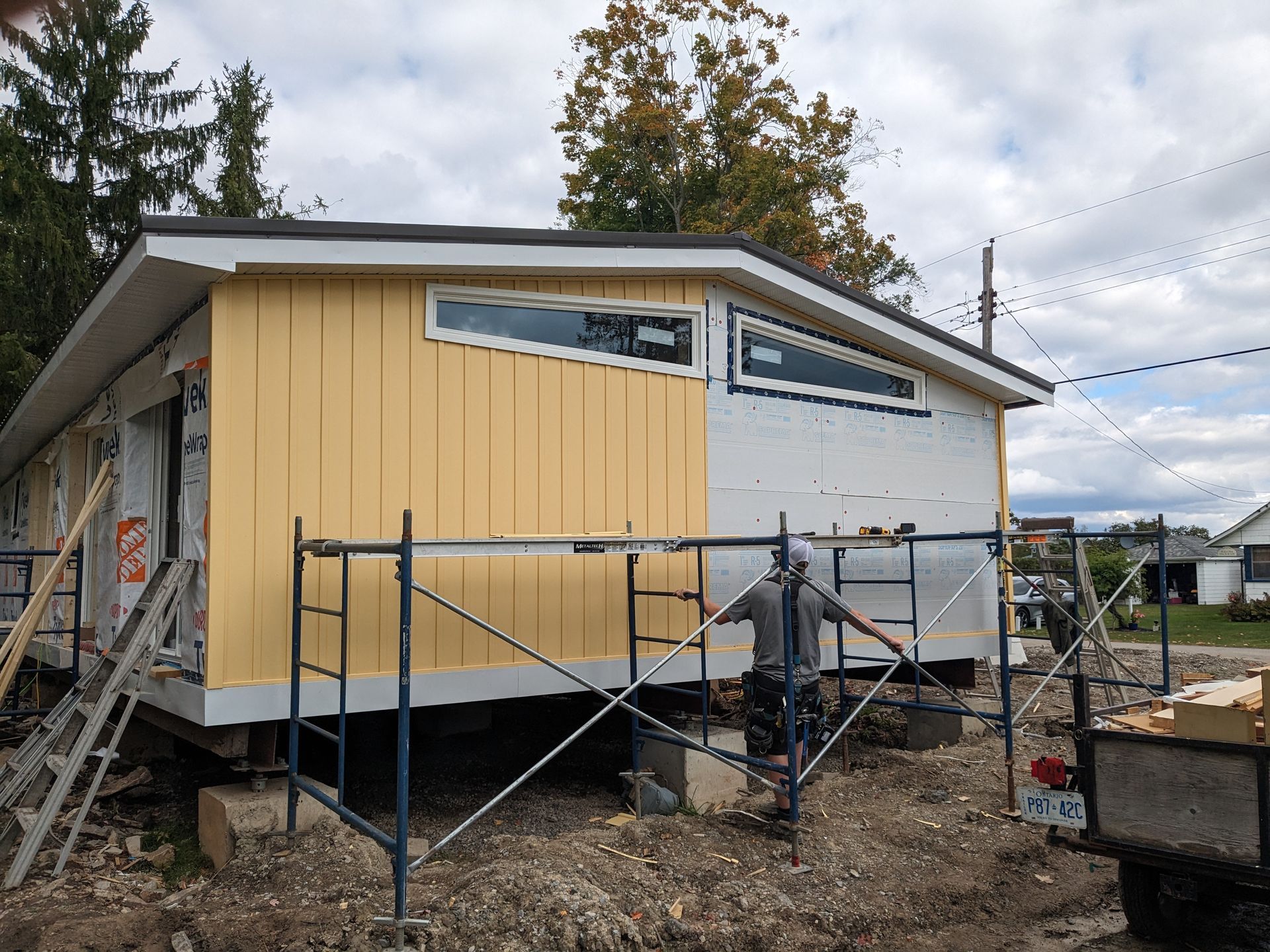 A yellow house is being built with scaffolding around it