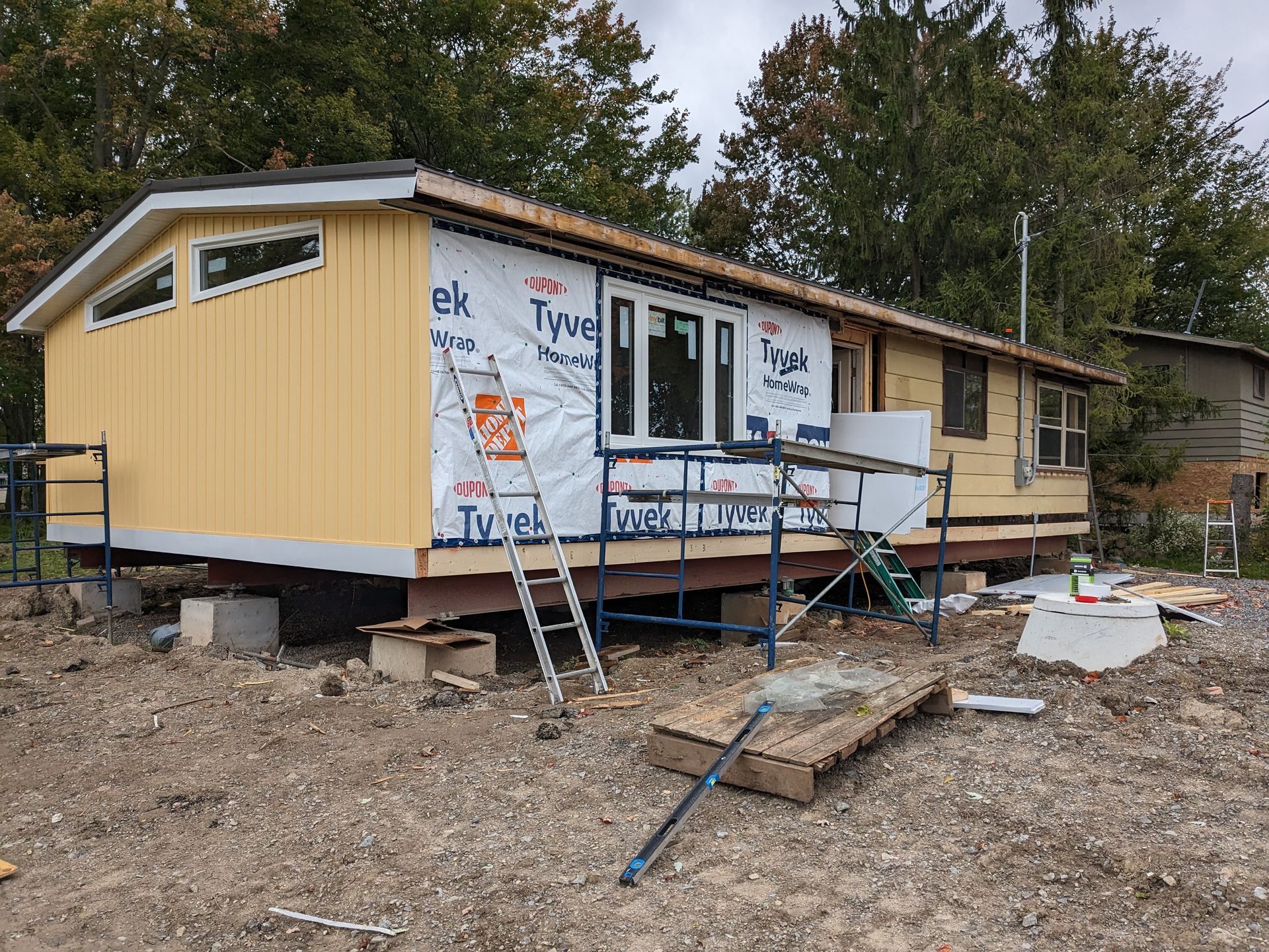 A yellow house is being built in a dirt field.