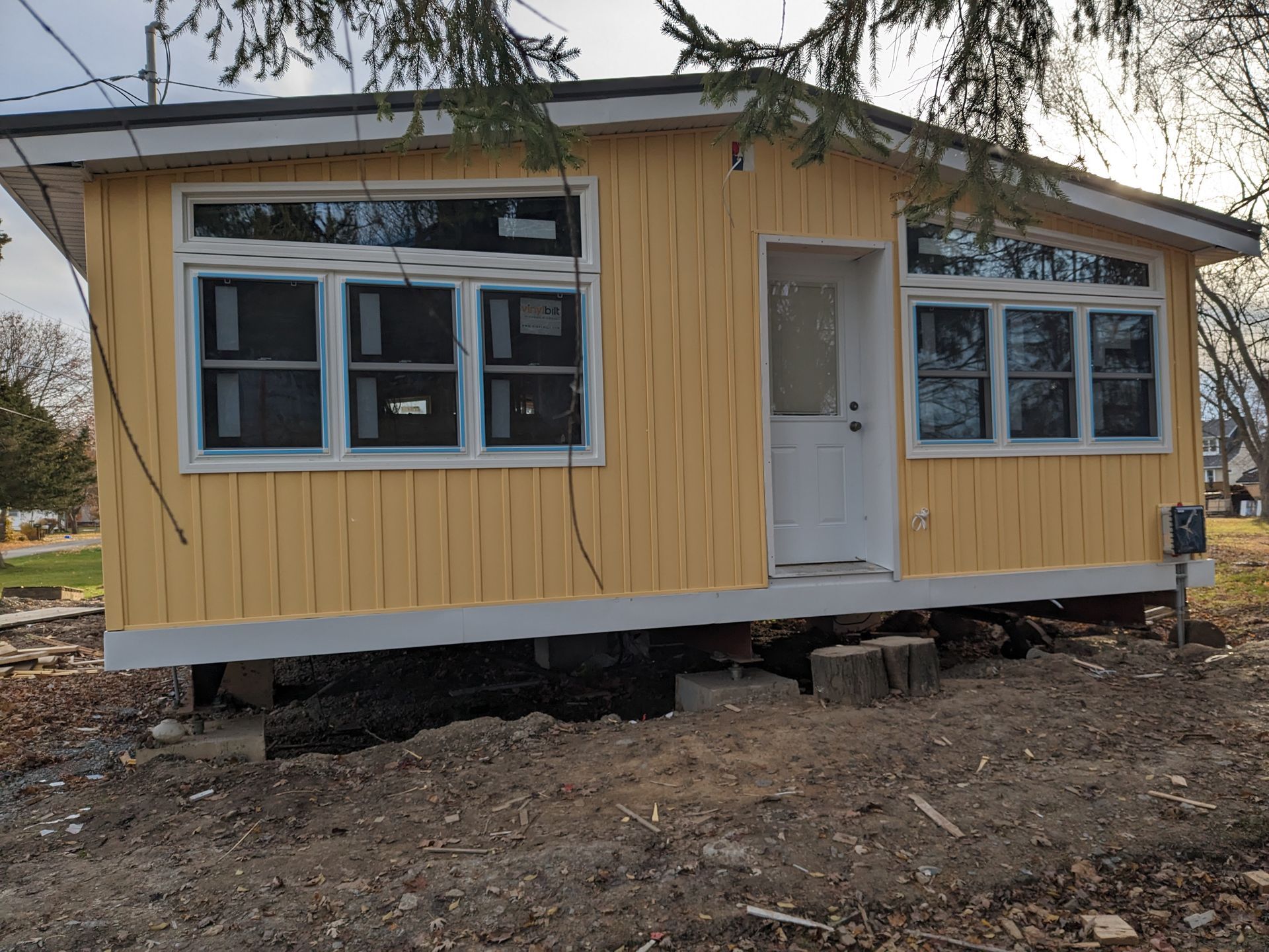 A small yellow house is sitting on top of a dirt field.