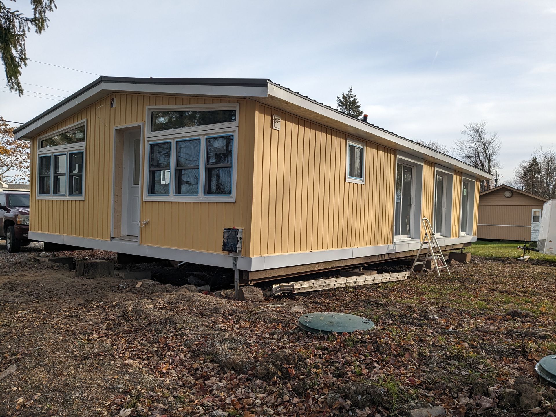 A yellow mobile home is sitting on top of a dirt field.