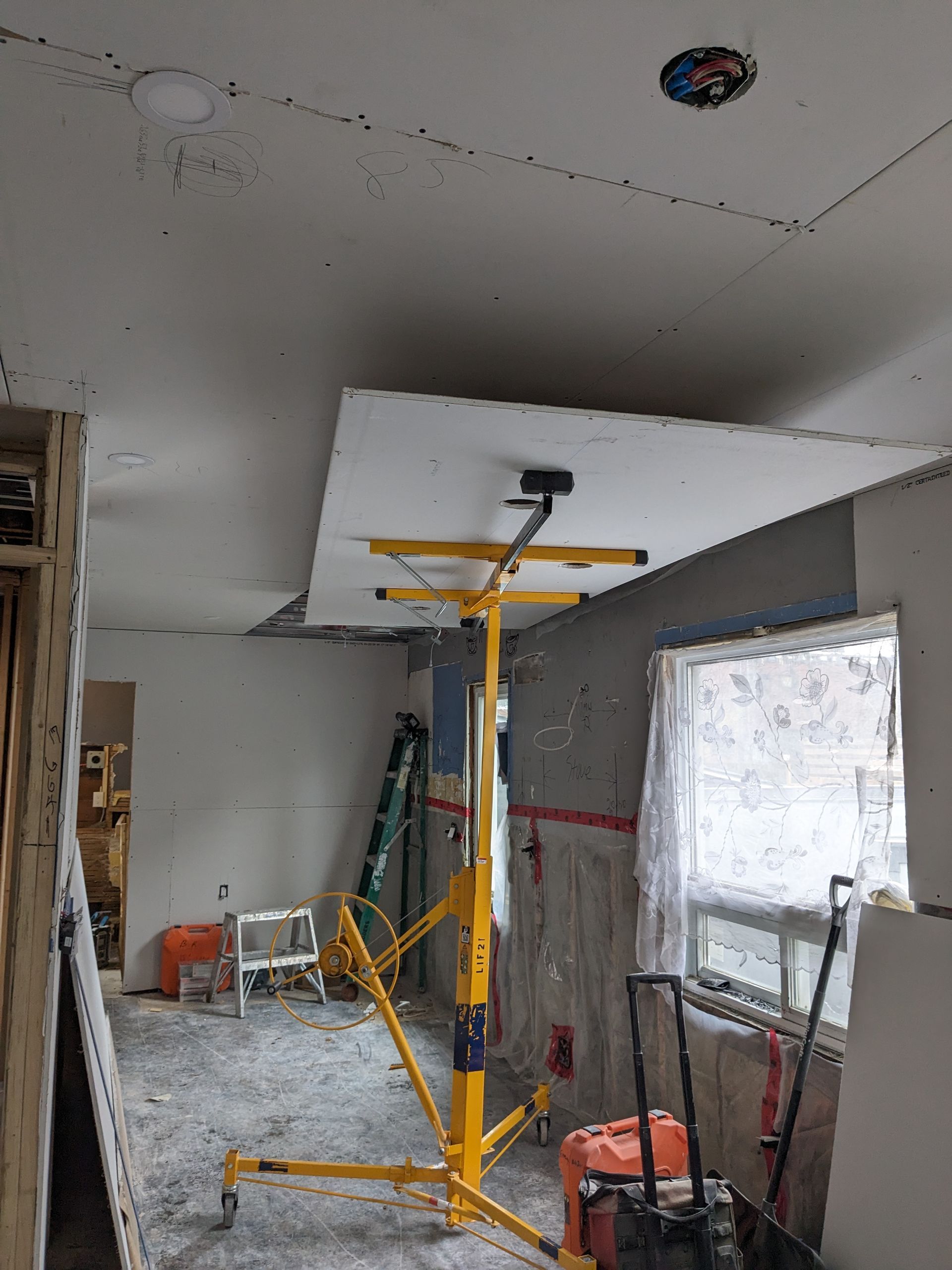 A room under construction with a ceiling lift and a ladder.