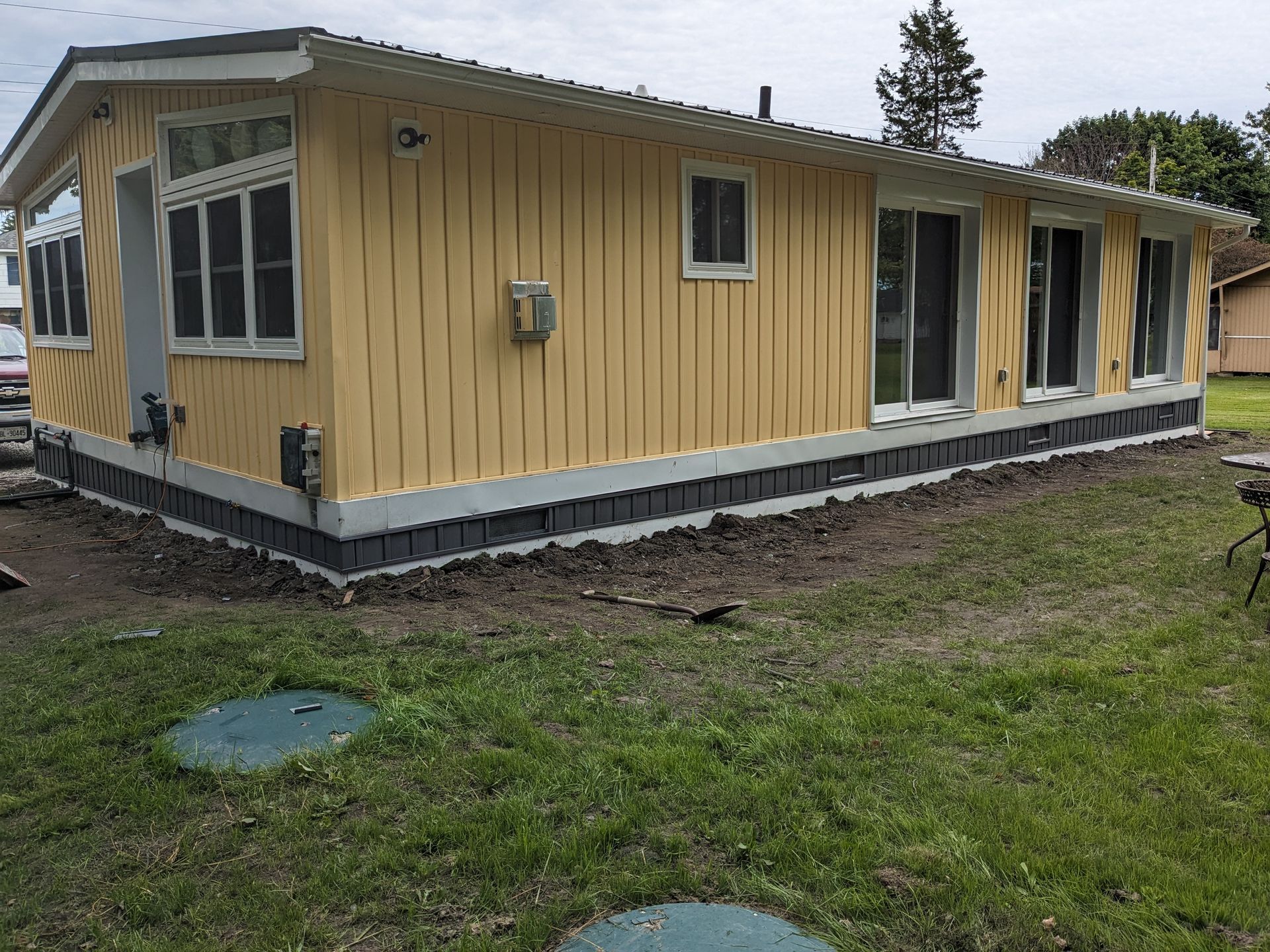 A yellow house is sitting on top of a lush green field.