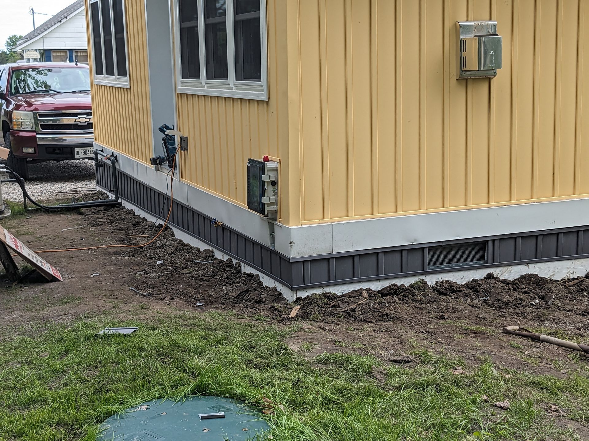 A yellow house with a red truck parked in front of it.