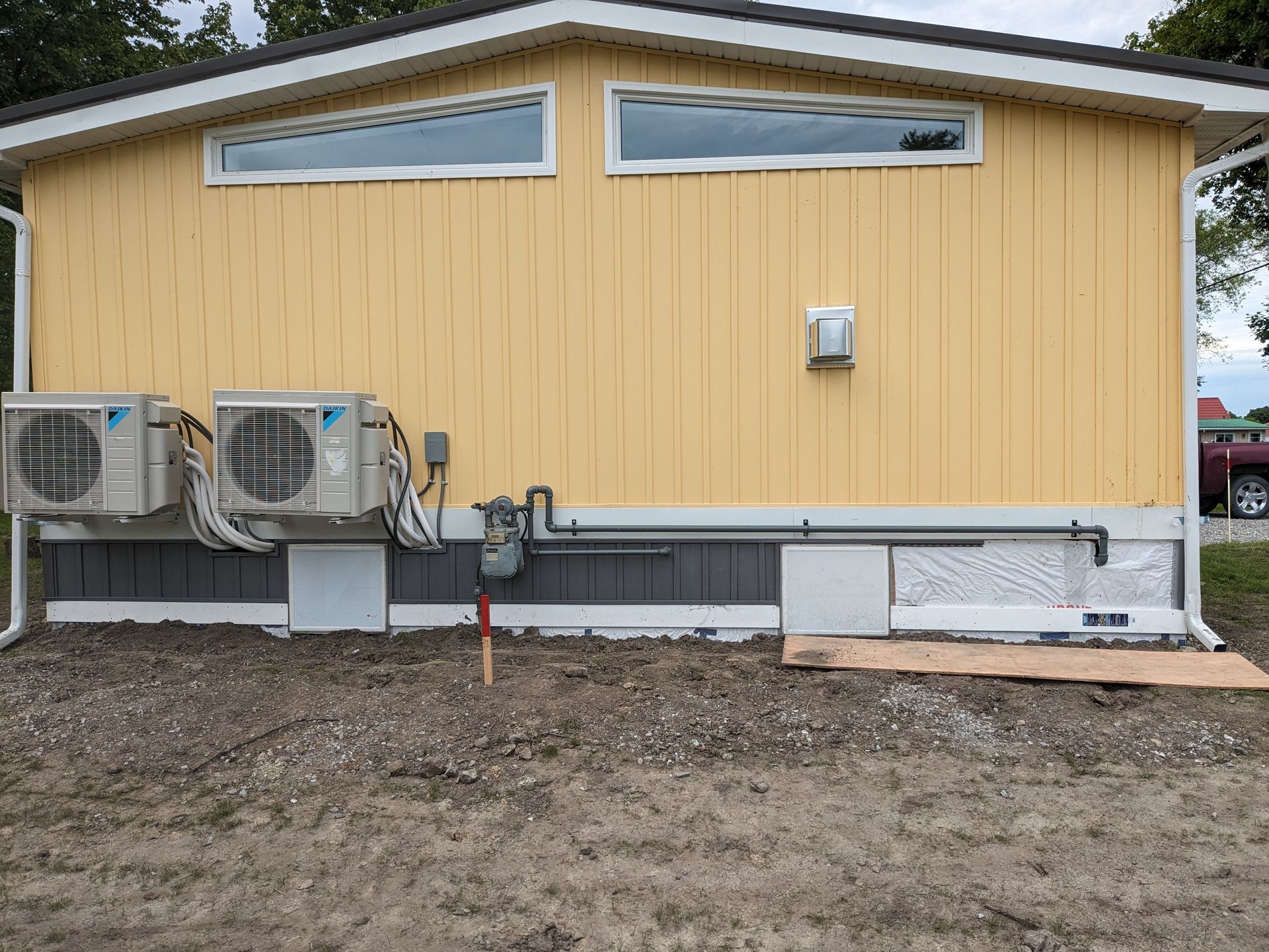 A yellow house with two air conditioners on the side of it.