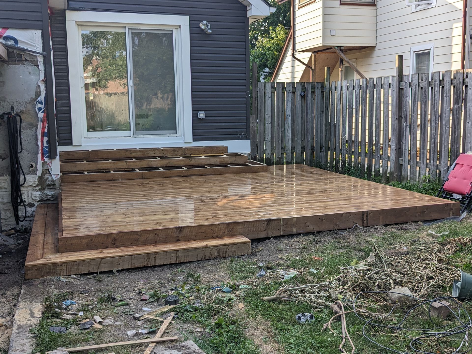 A wooden deck is being built in the backyard of a house.