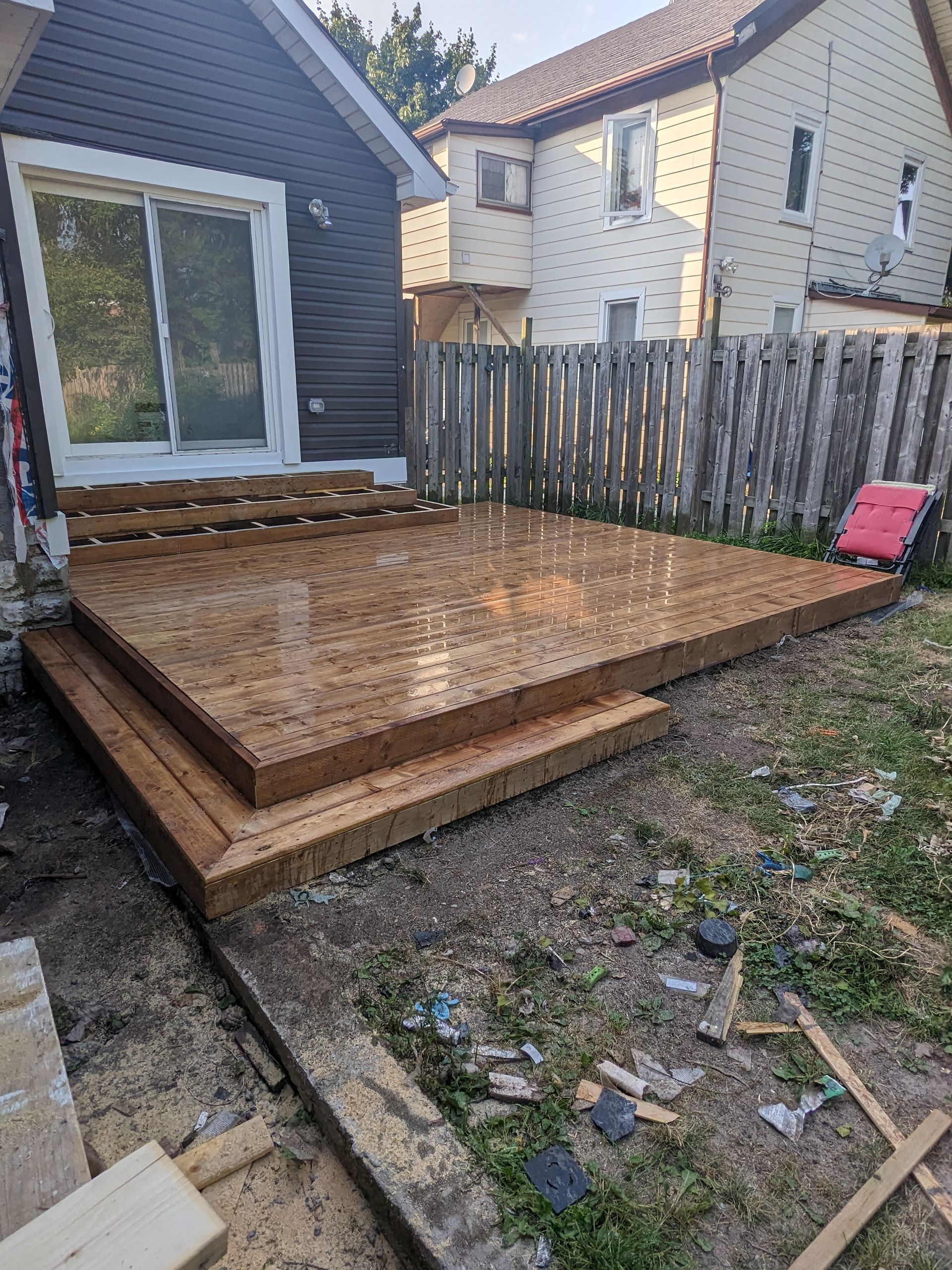 A wooden deck is being built in the backyard of a house.