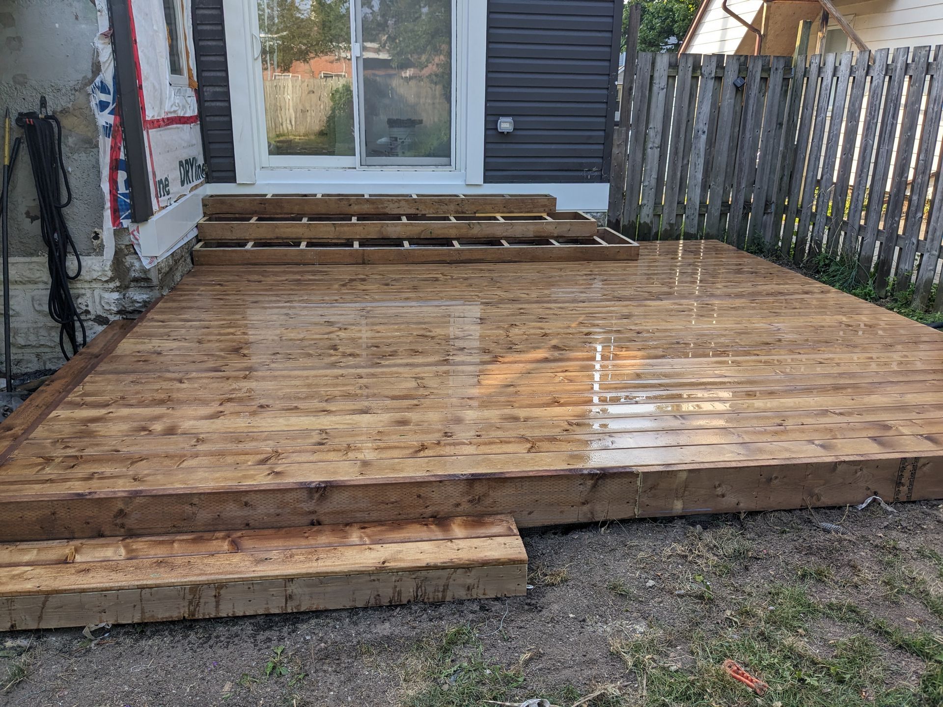 A wooden deck is being built in the backyard of a house.