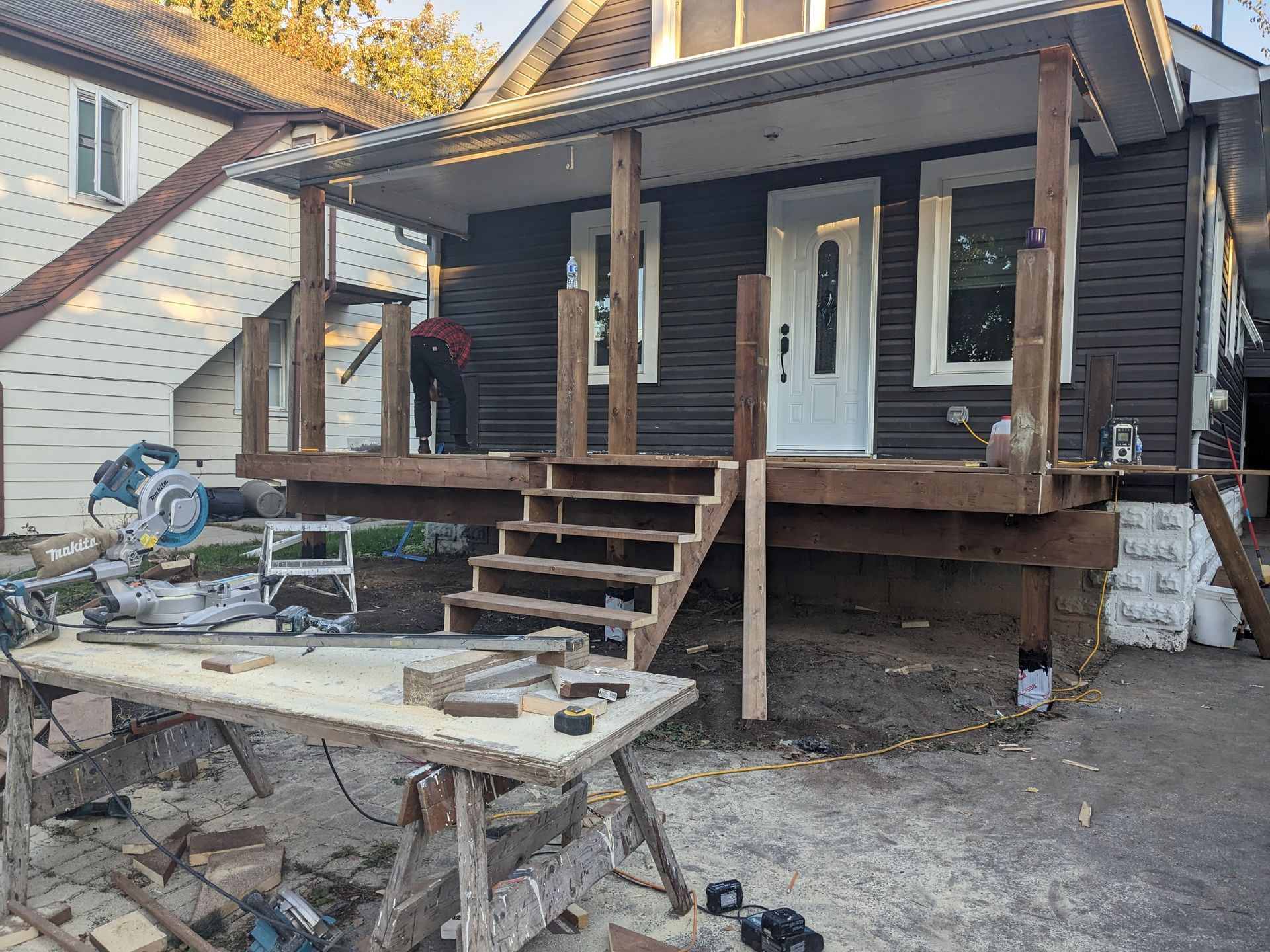 A wooden deck is being built in front of a house.