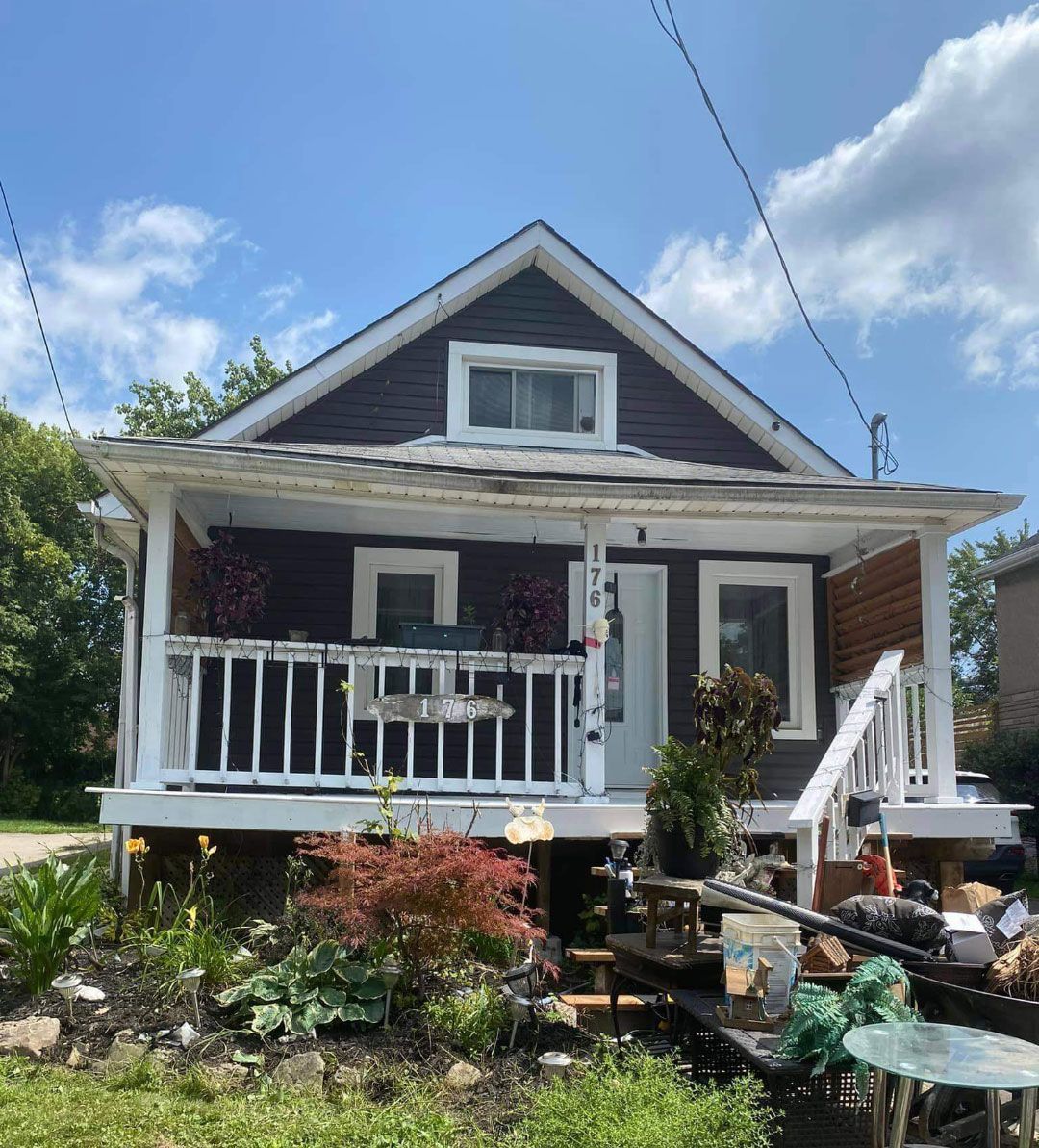 A small house with a porch and stairs on a sunny day.