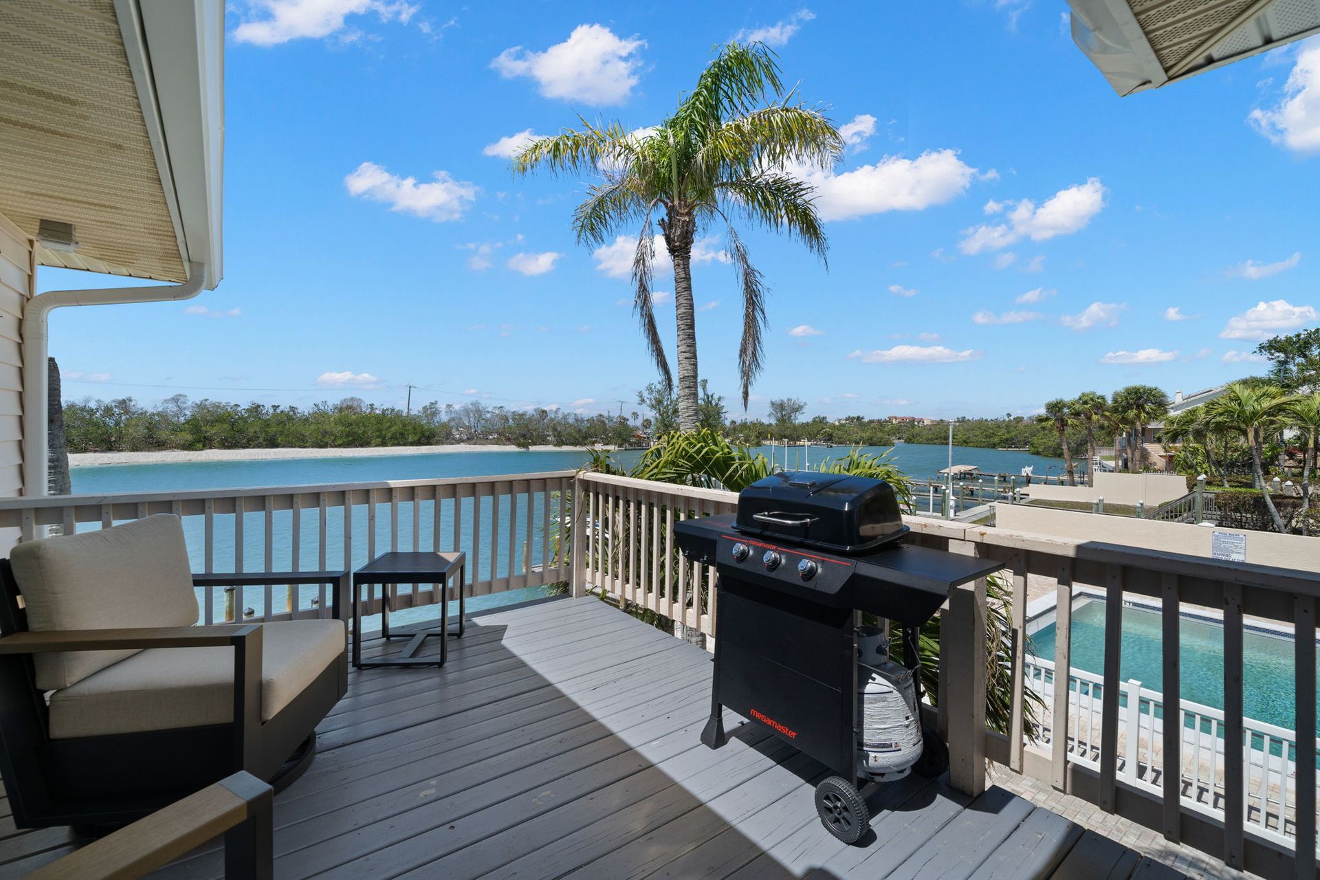 A grill is sitting on a deck overlooking a body of water.