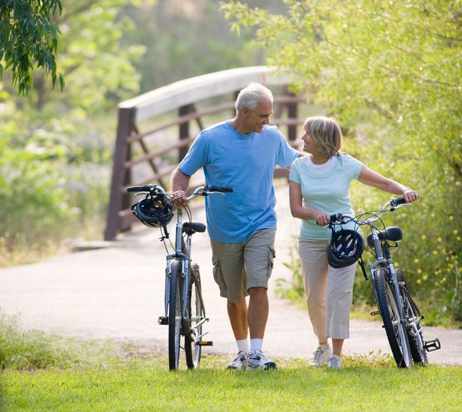An Old Man and a Woman Walking With Bicycles — Budd & Piper Solicitors & Conveyancers in Tweed Heads, NSW