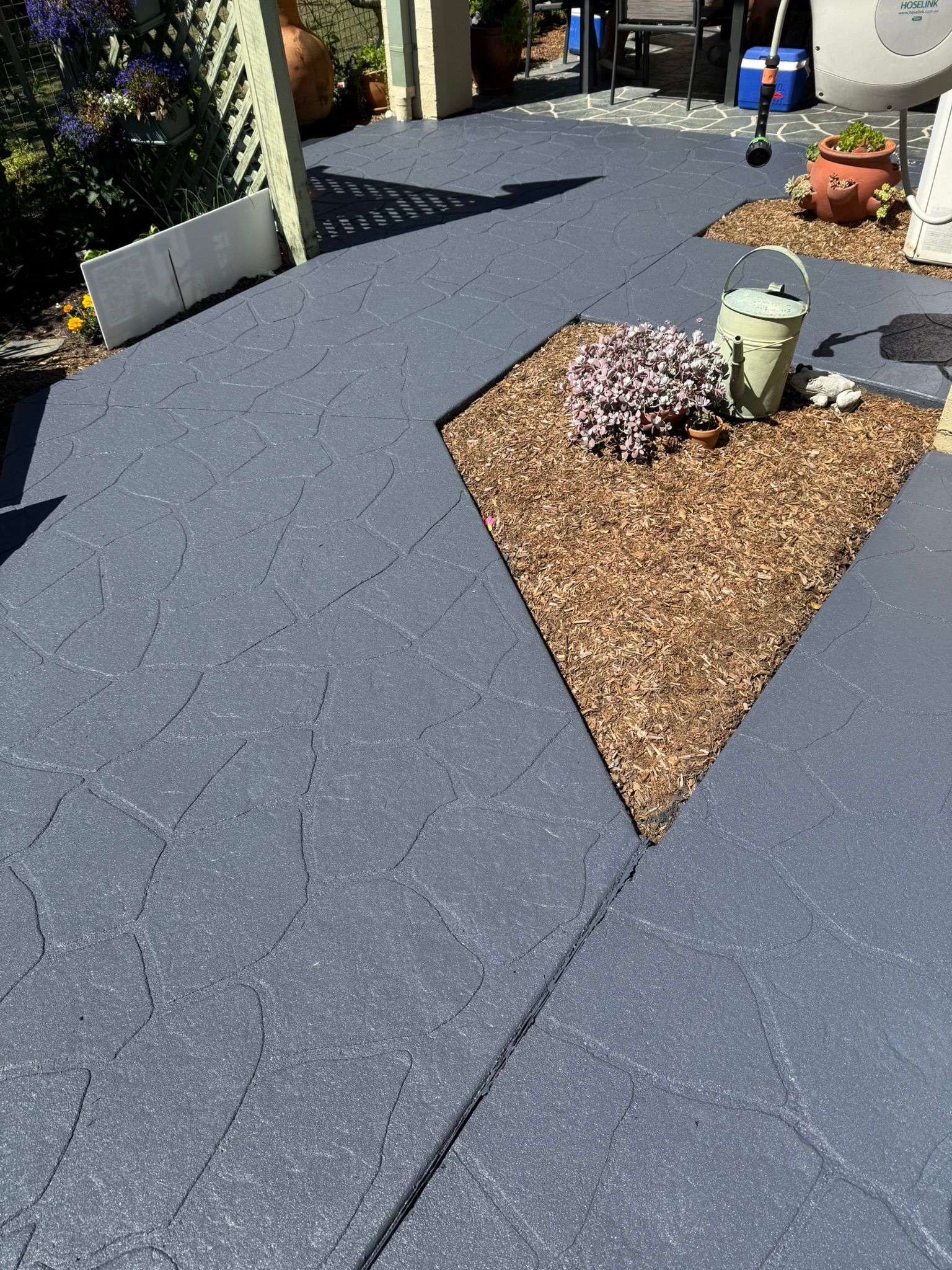 Construction Worker Kneeling, Smoothing Cement Into a Road Crack — Port Macquarie Concrete Resurfacing in Port Macquarie, NSW