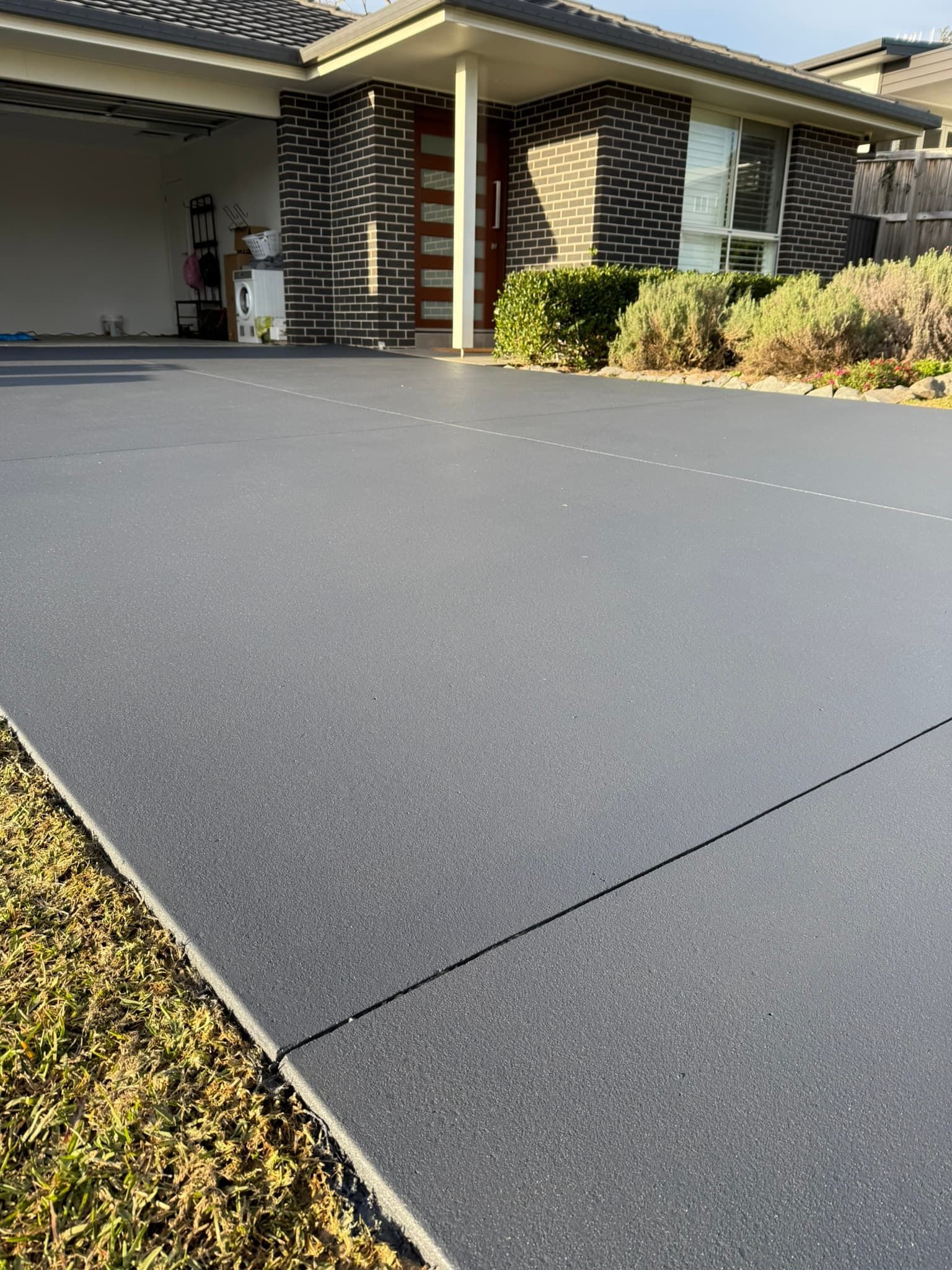 Grey Concrete Driveway Leading to A Modern Brick House — Port Macquarie Concrete Resurfacing in Port Macquarie, NSW