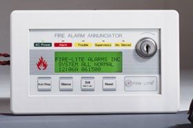 A fire alarm with a key on it is sitting on a table.