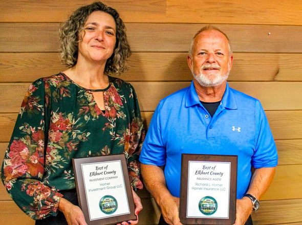 Kim Roberts and Rich Horenr holding framed awards, smiling, against a wooden background.