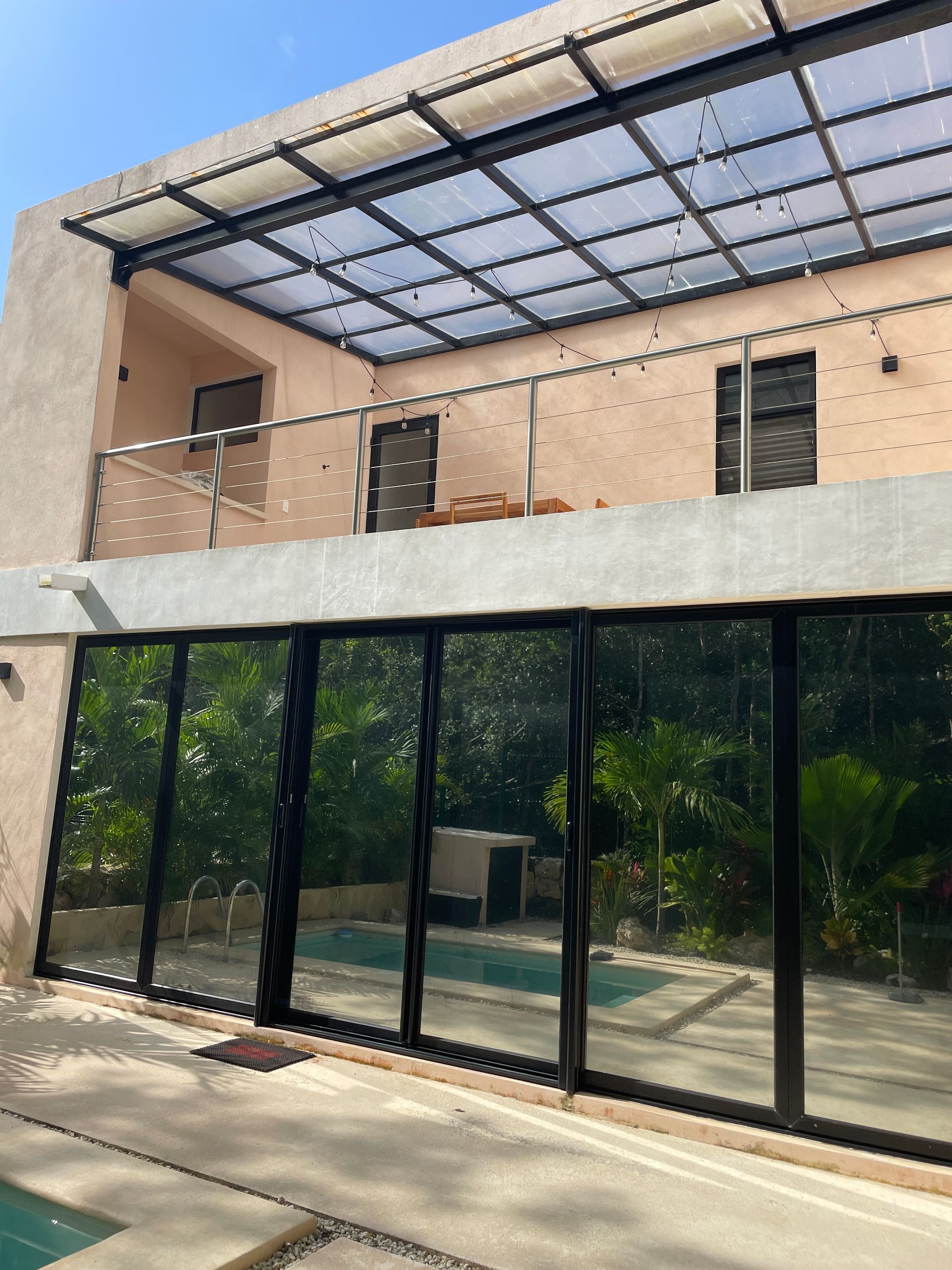 Fachada trasera con reflejo de jardin y alberca