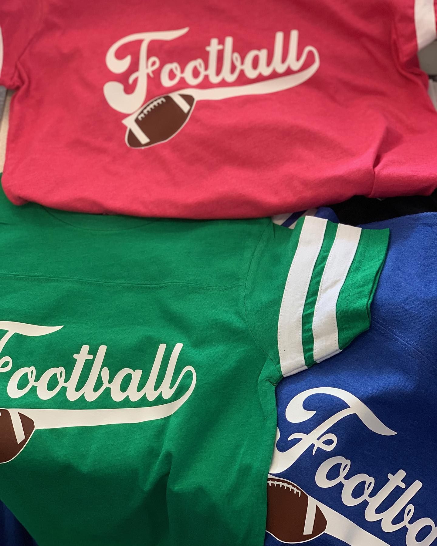 Three different colored football shirts are stacked on top of each other