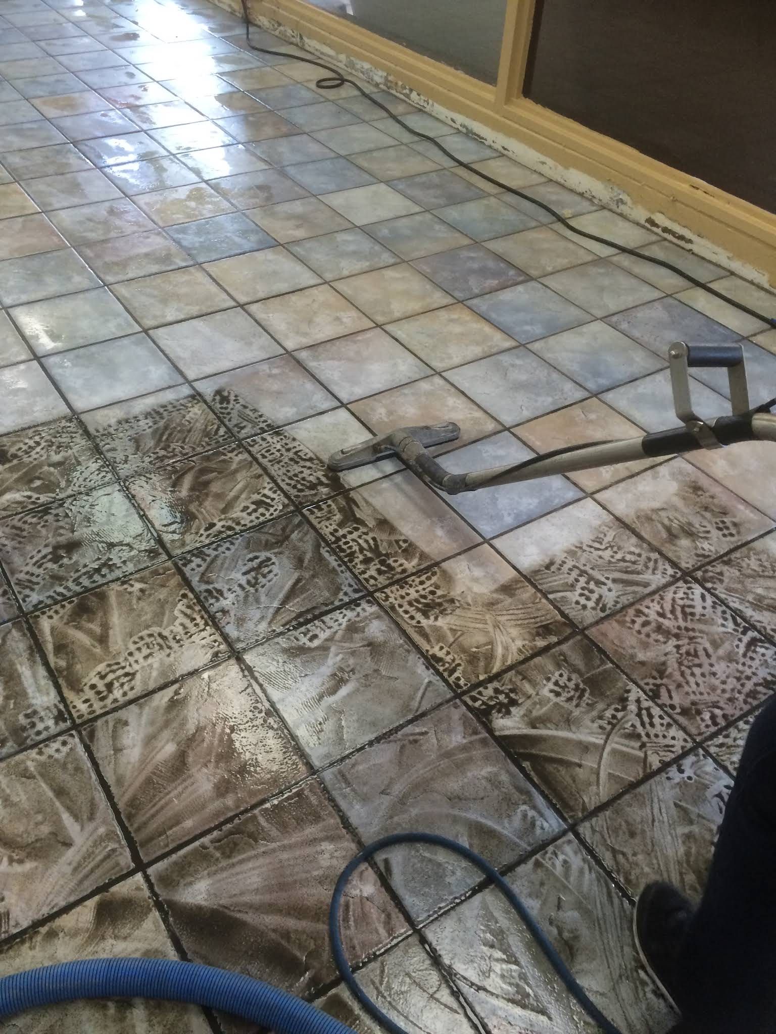 Cleaning ceramic tiled floor with a machine. Wet floor with a portion cleaned.