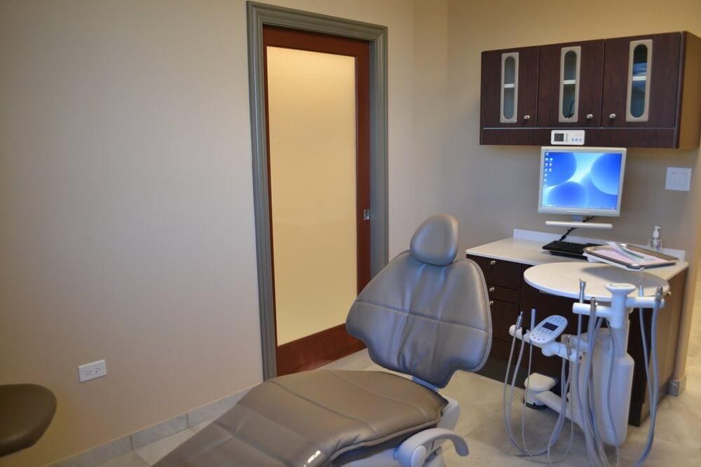 A dental office with a chair and a computer