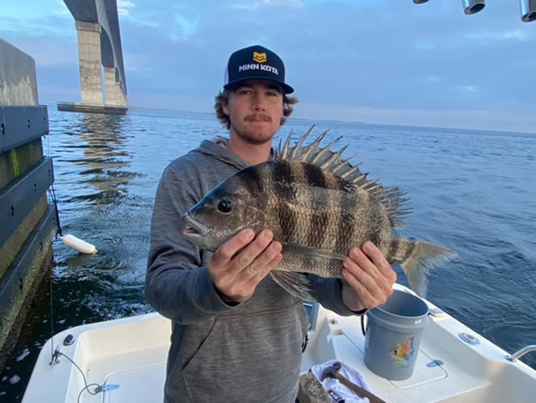 A man is holding a large fish on a boat.
