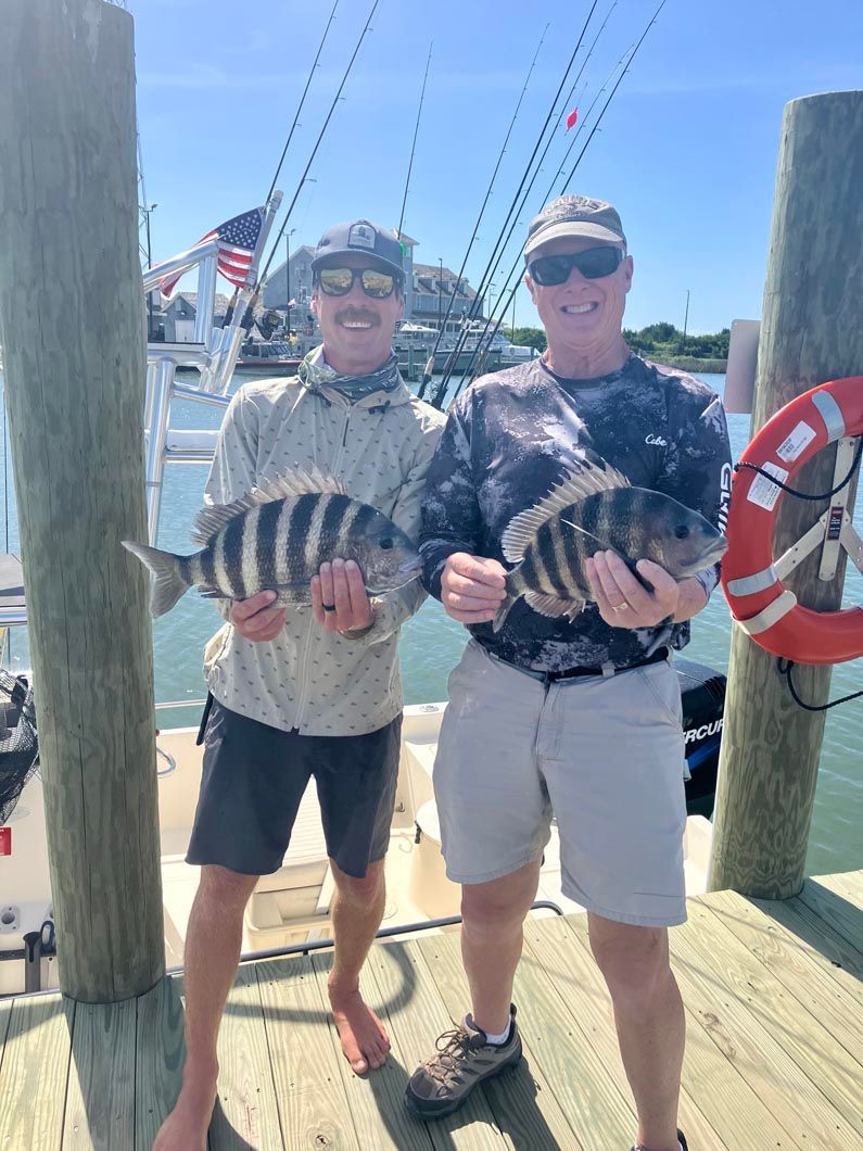 Two men are standing on a dock holding fish.