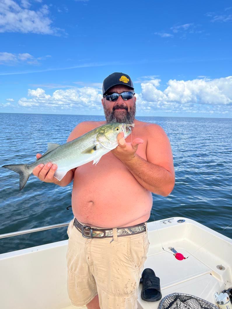 A man is holding a fish on a boat in the ocean.