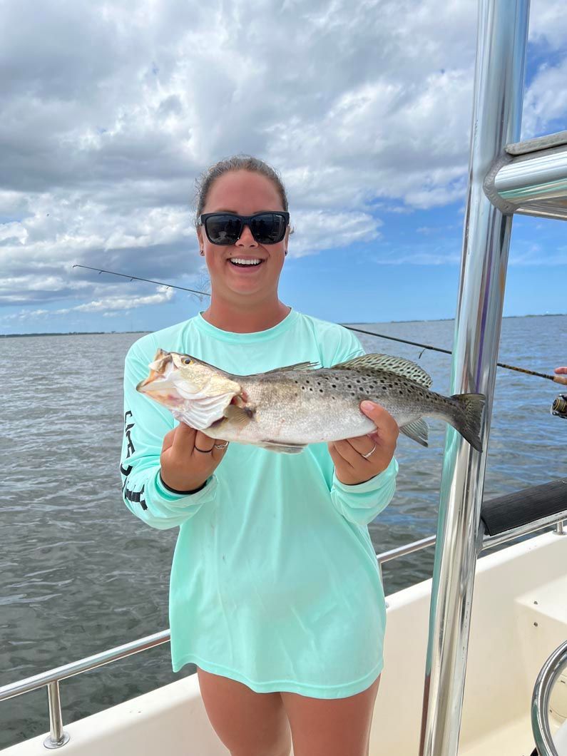 A woman is holding a fish on a boat.