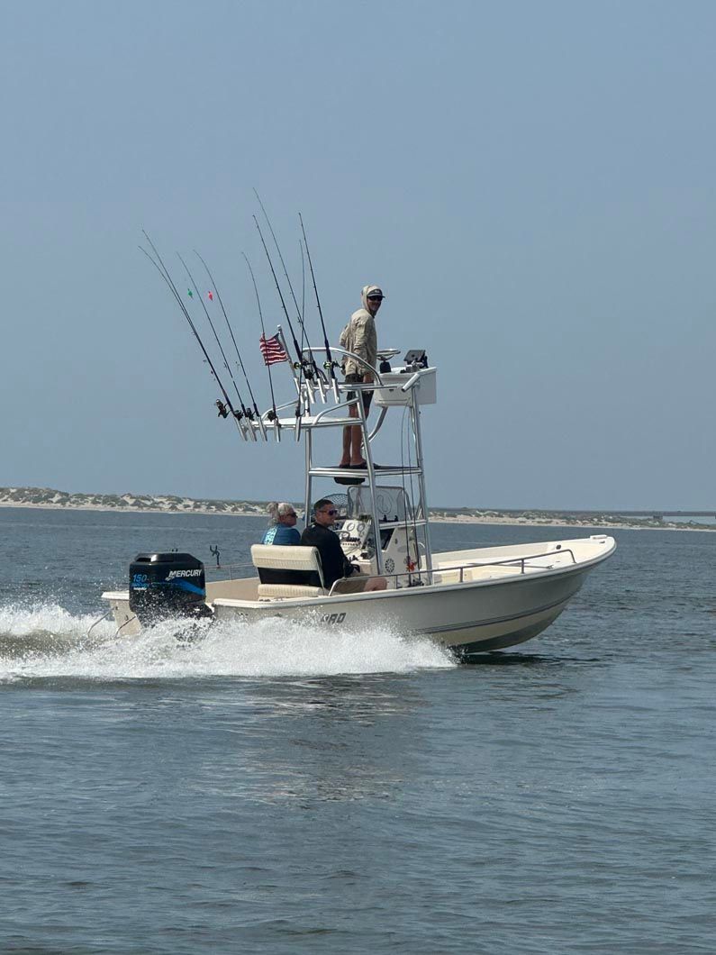 A man is standing on top of a boat in the water.